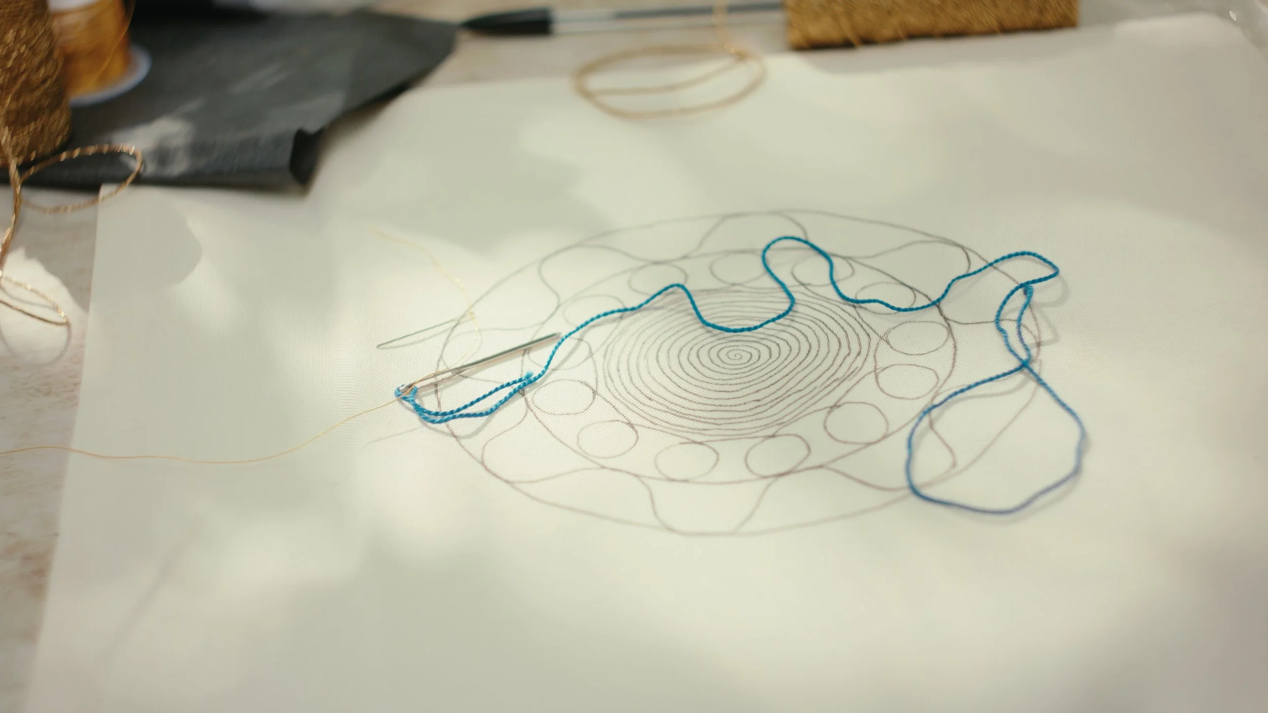 Tahriri couching embroidery in progress with blue cord laid over a drawn pattern