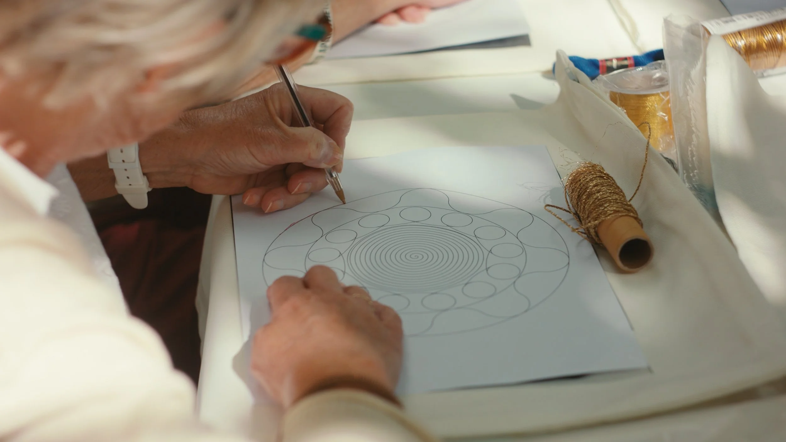 Participant tracing a circular embroidery pattern during a Palestinian tahriri workshop with The Tatreez Collective.