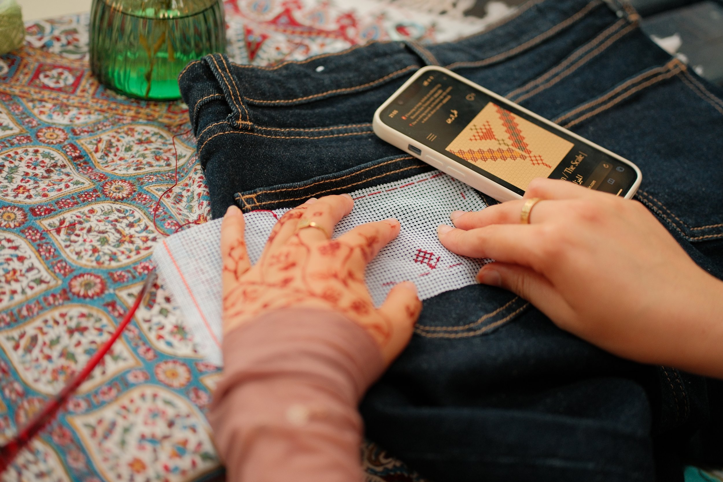 Participant learning Palestinian tatreez embroidery on denim during a hands-on workshop by The Tatreez Collective.