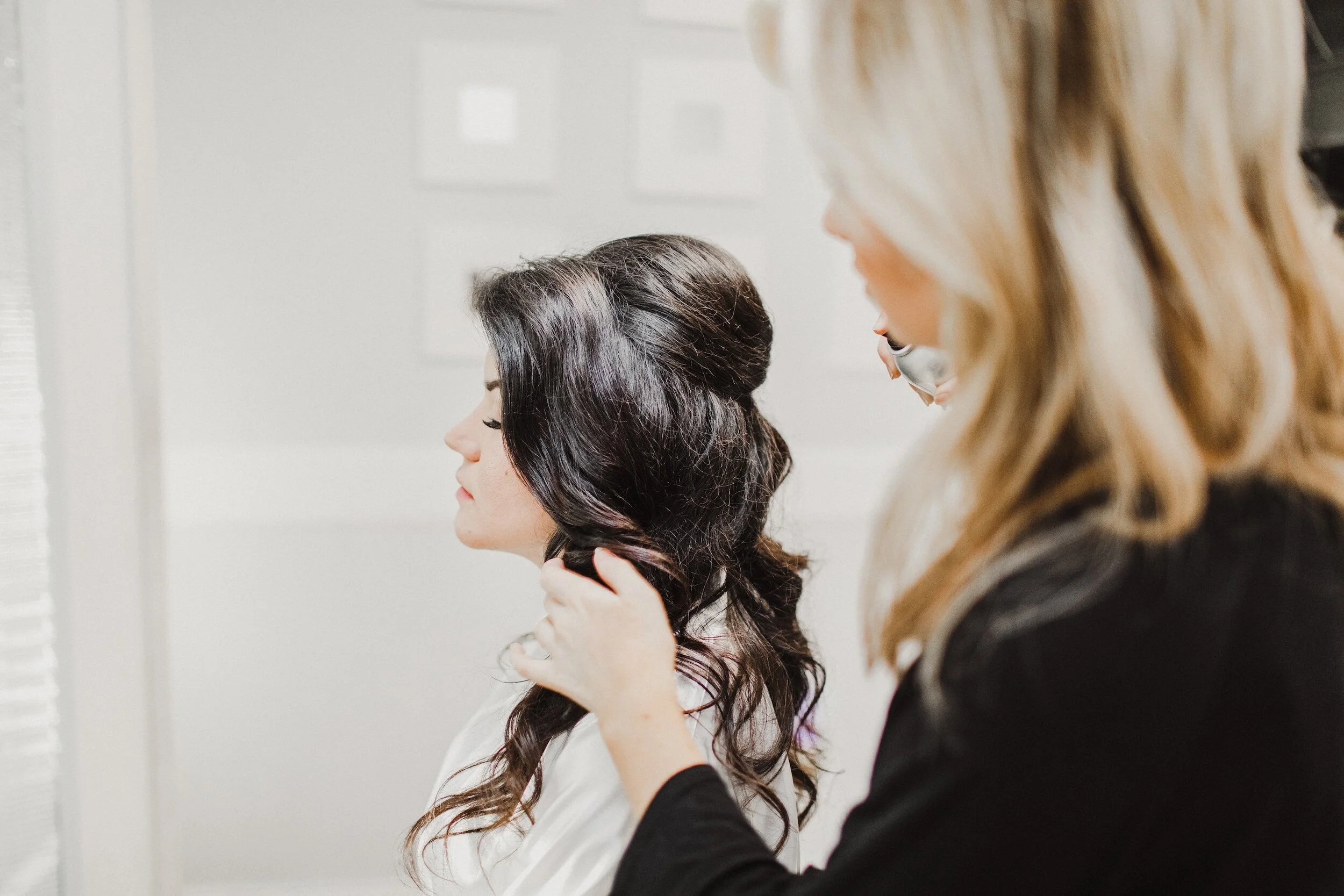 Hairstylist working on woman's hair, creating an elegant updo.