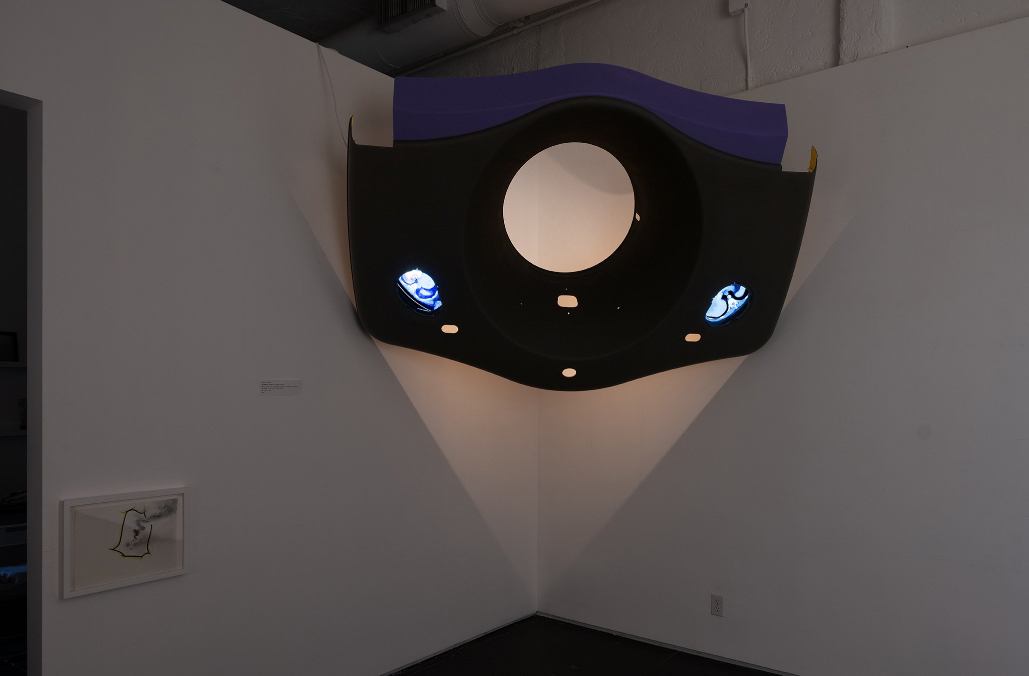 The Oracle’s Retort: La Luna y El Sol, 2026, Gantry cover of GE LightSpeed CT scanner, HD videos of personal sonagrams and CT scans, light fixture, 60”(h) x 36”(d) x 84” (w)