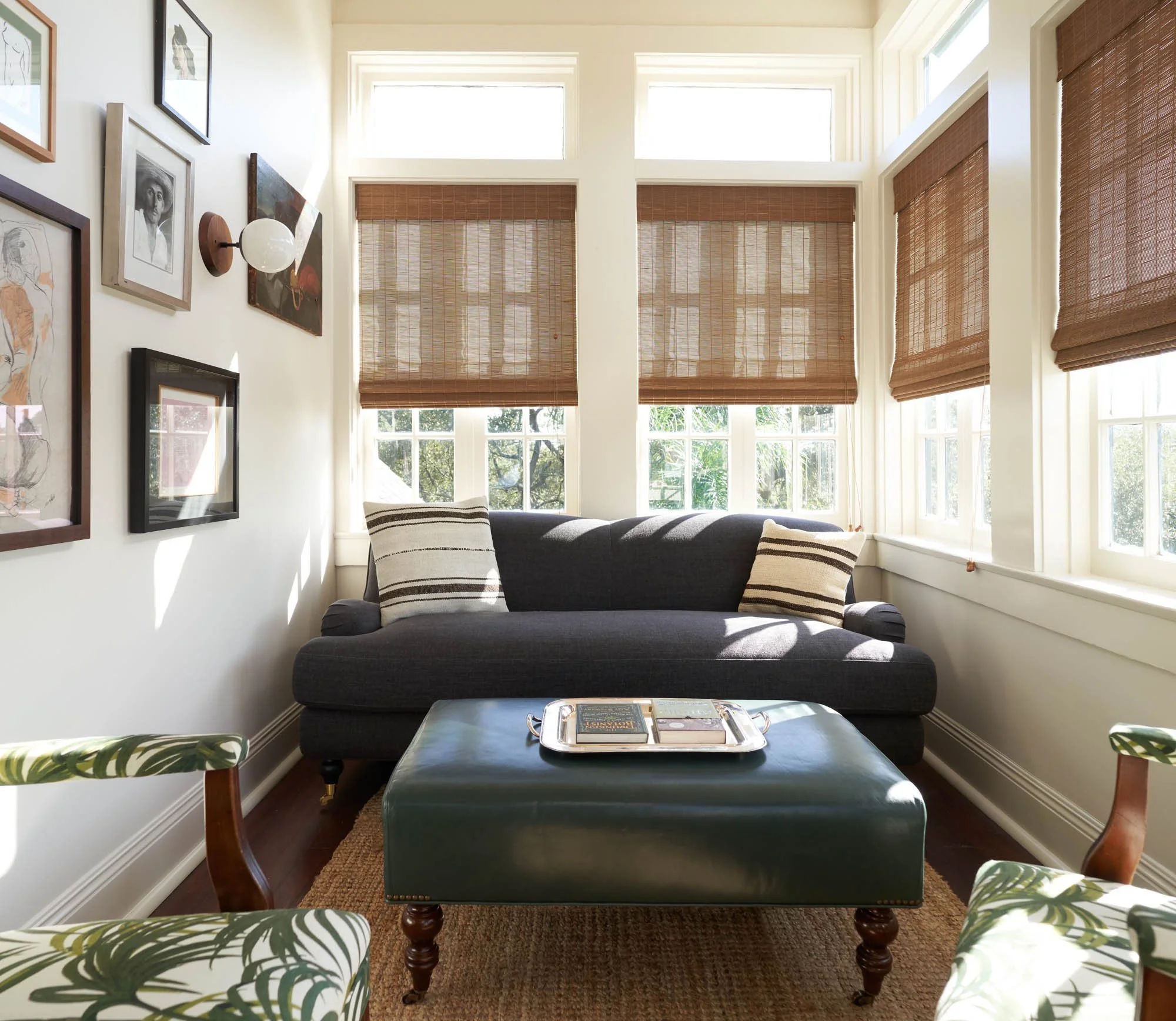 The Chloe's Avenue Double Queen Suite with a comfortable couch, a stylish ottoman, and elegant window shades.