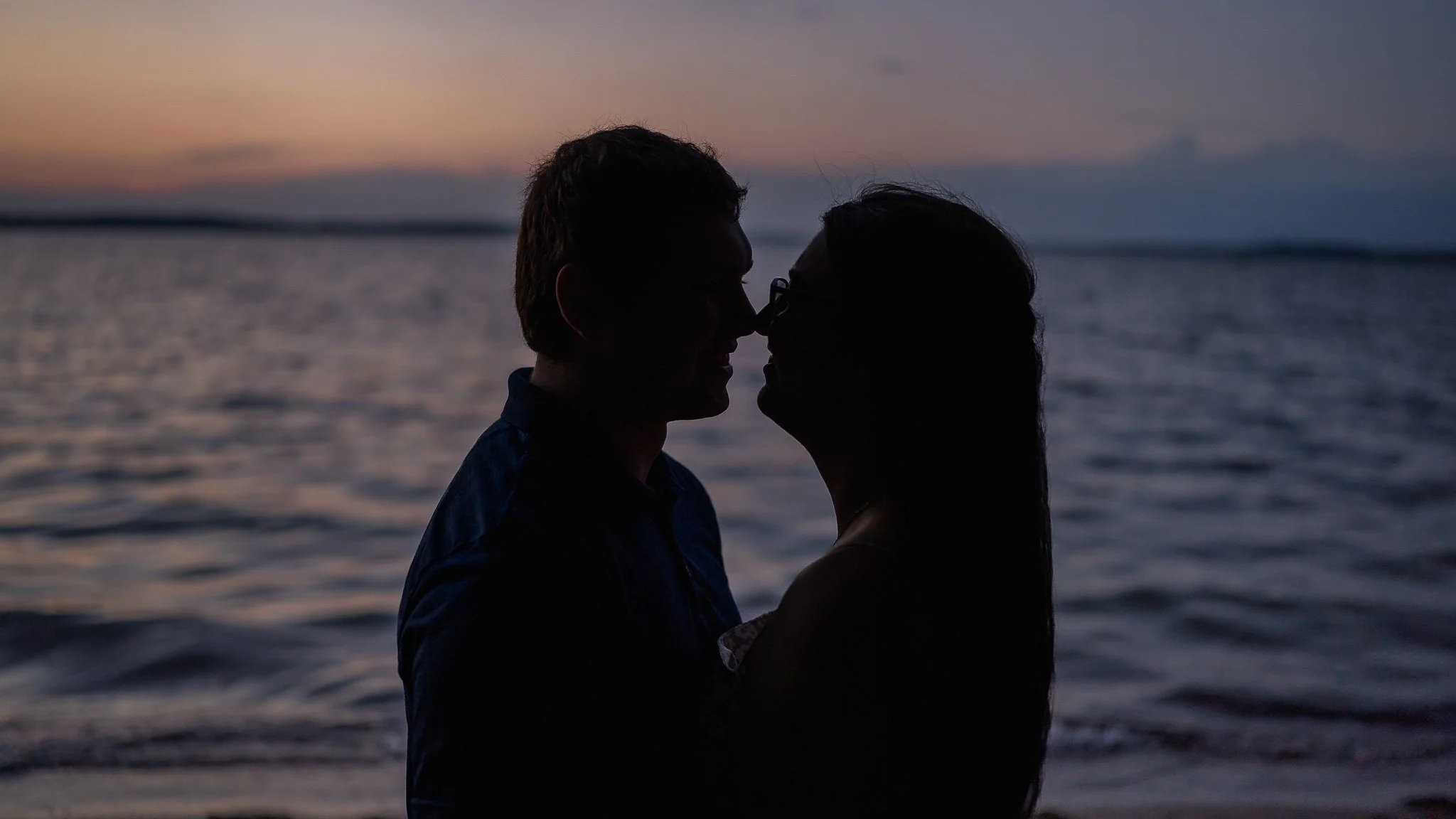 Silhouette of a couple facing each other and about to kiss on the beach at sunset
