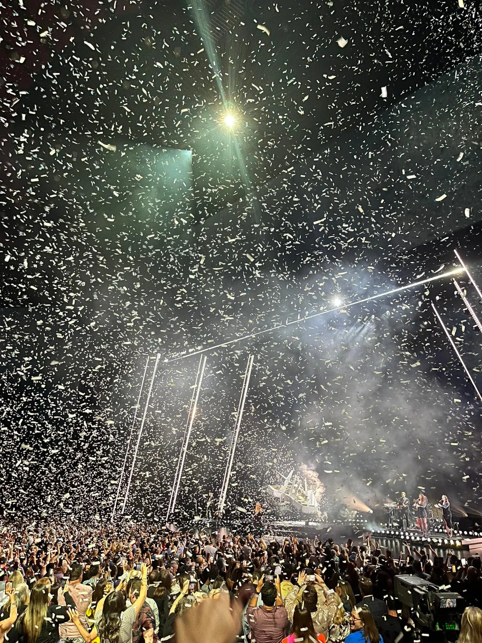 A concert with a large crowd, fireworks, and confetti in the air.