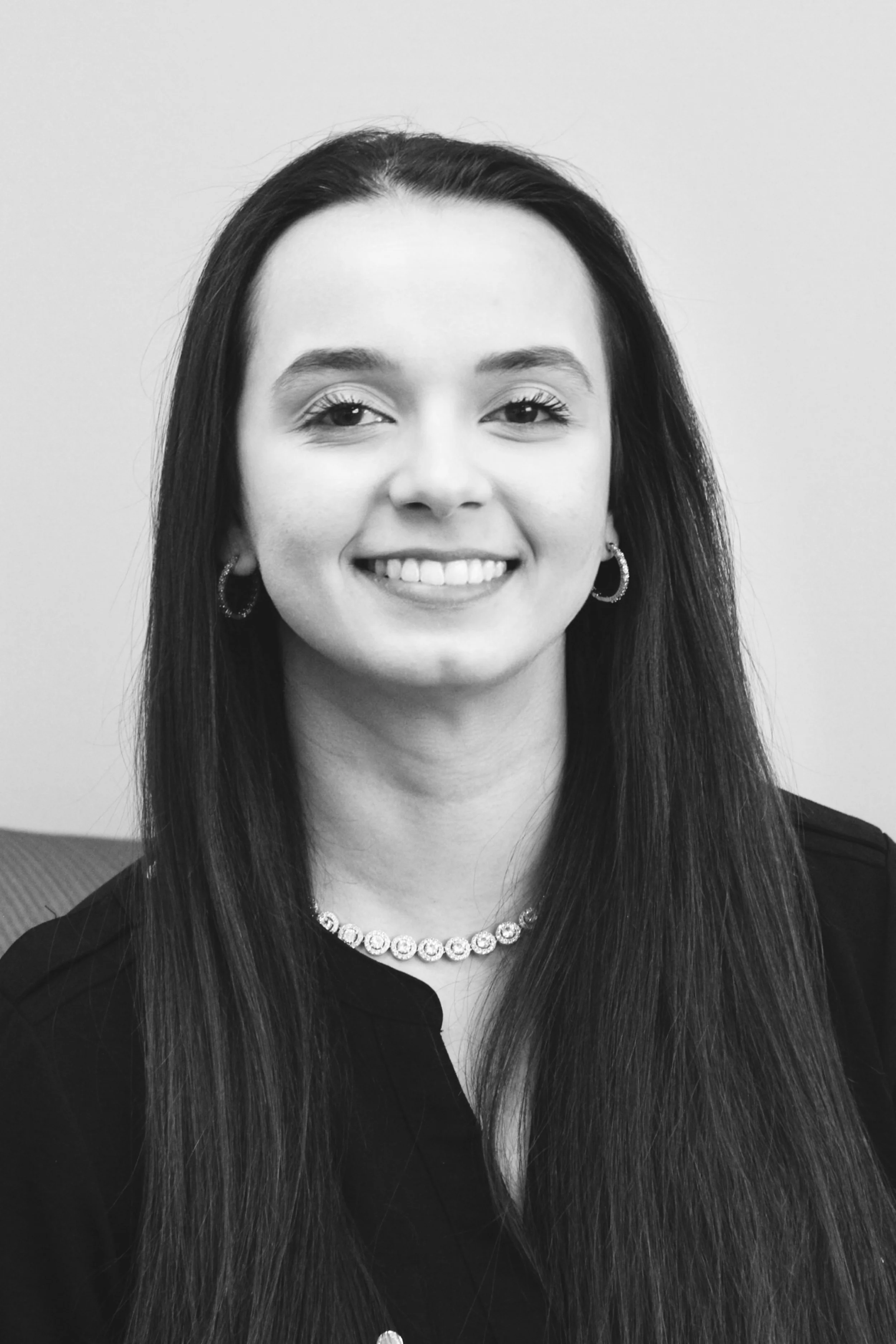 Black and white portrait of a smiling woman with long hair and hoop earrings.