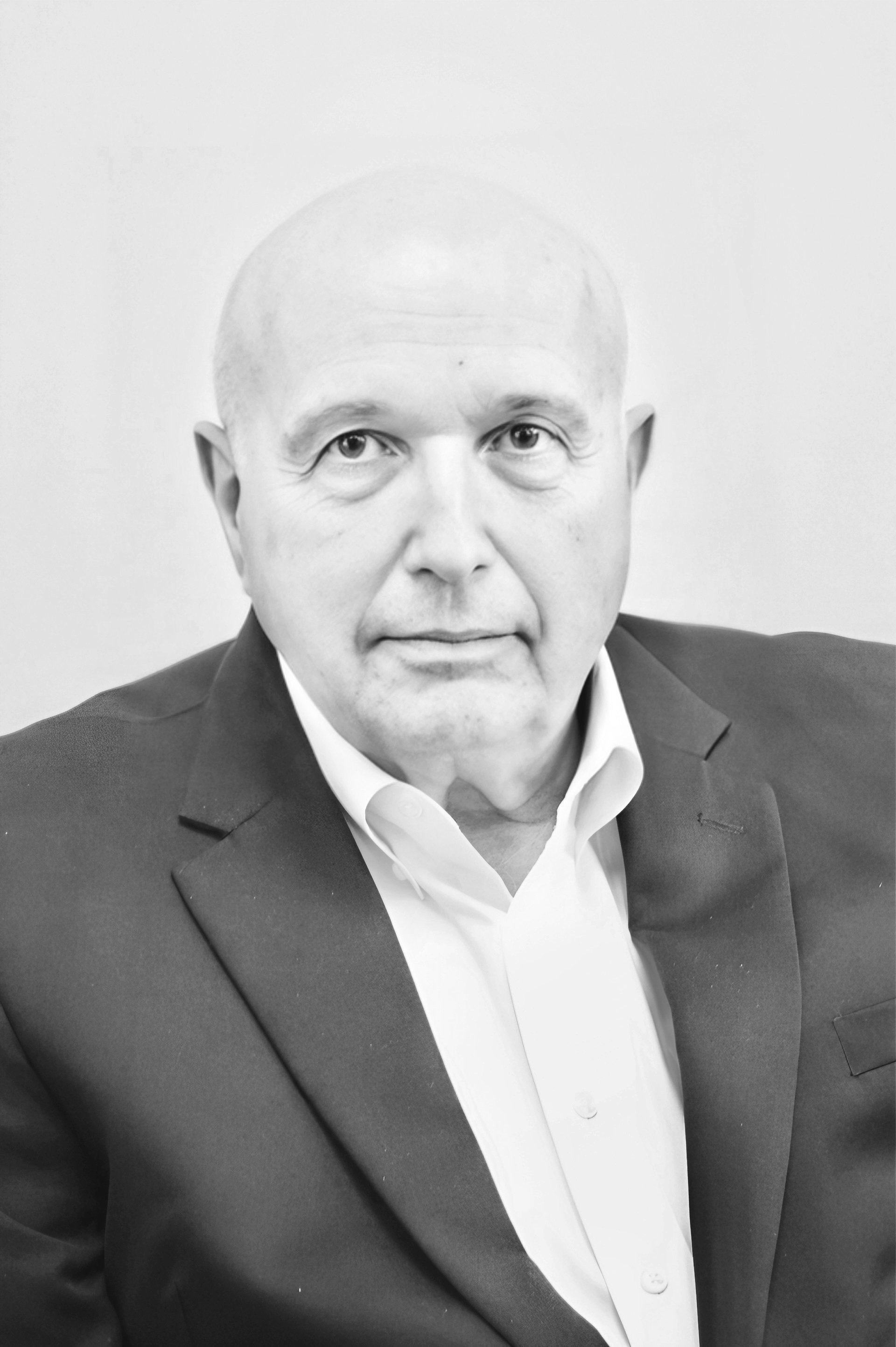 Black and white portrait of a balding man wearing a suit jacket and white shirt.