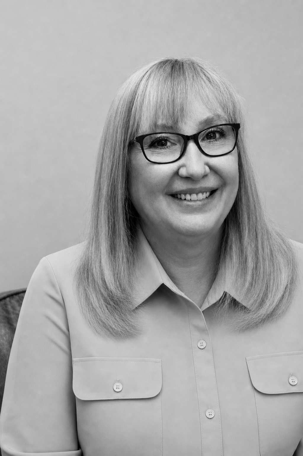 Black and white portrait of a smiling woman with long, wavy hair, wearing a button-up shirt.