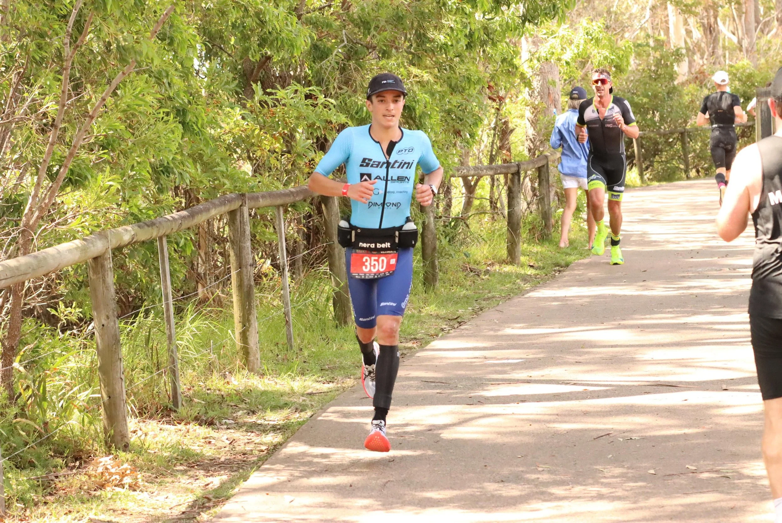 Athlete in blue Santini tri suit running along a tree-lined path during a triathlon race, wearing race bib number 350.