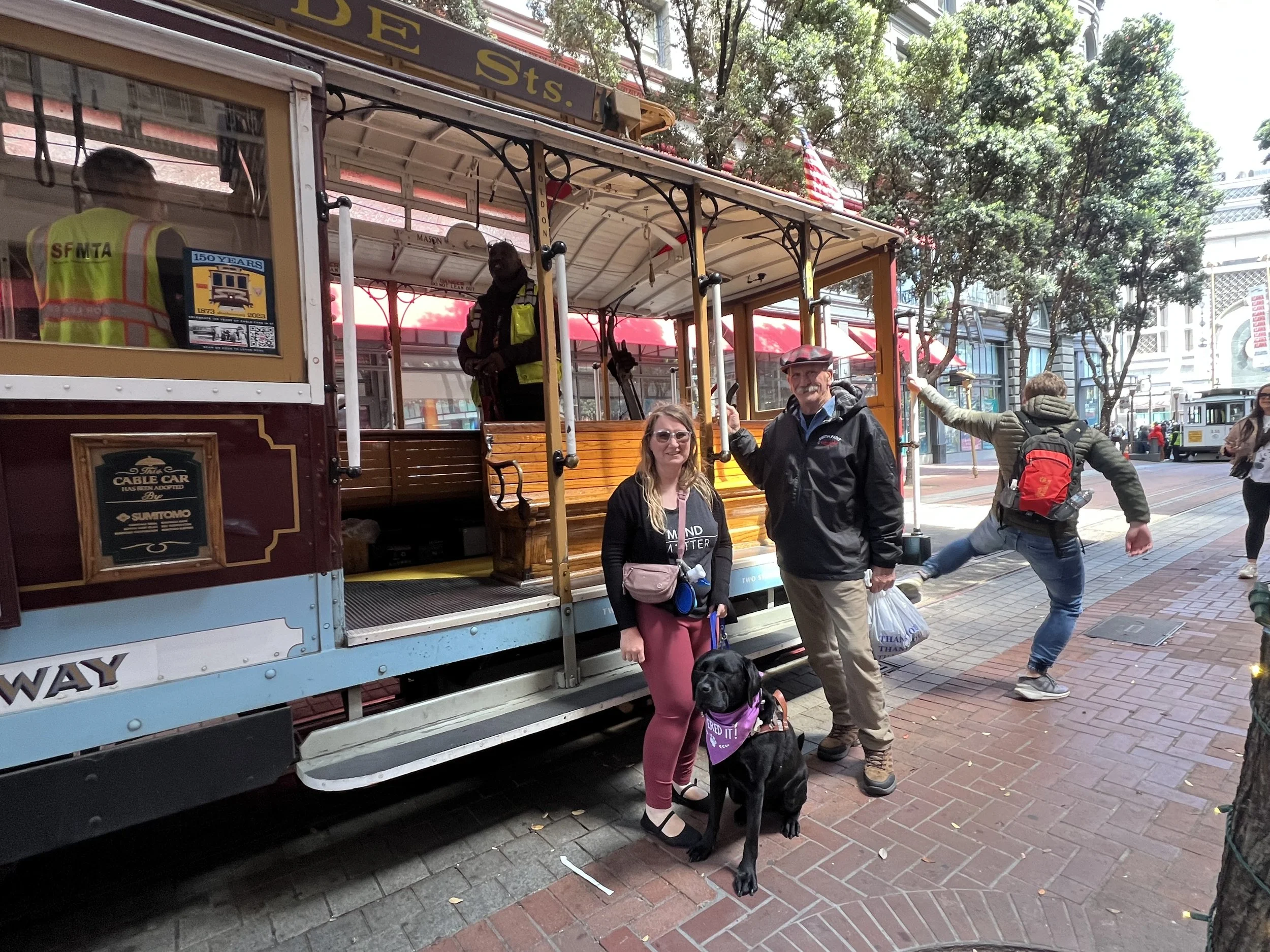 Lindsay, Eve, and her dad standing together in front of a trolley car in San Francisco.