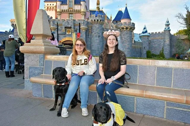 Eve, Lindsay, Shelbi, and Kristen sitting in front of Cinderella’s castle in Disneyland.  