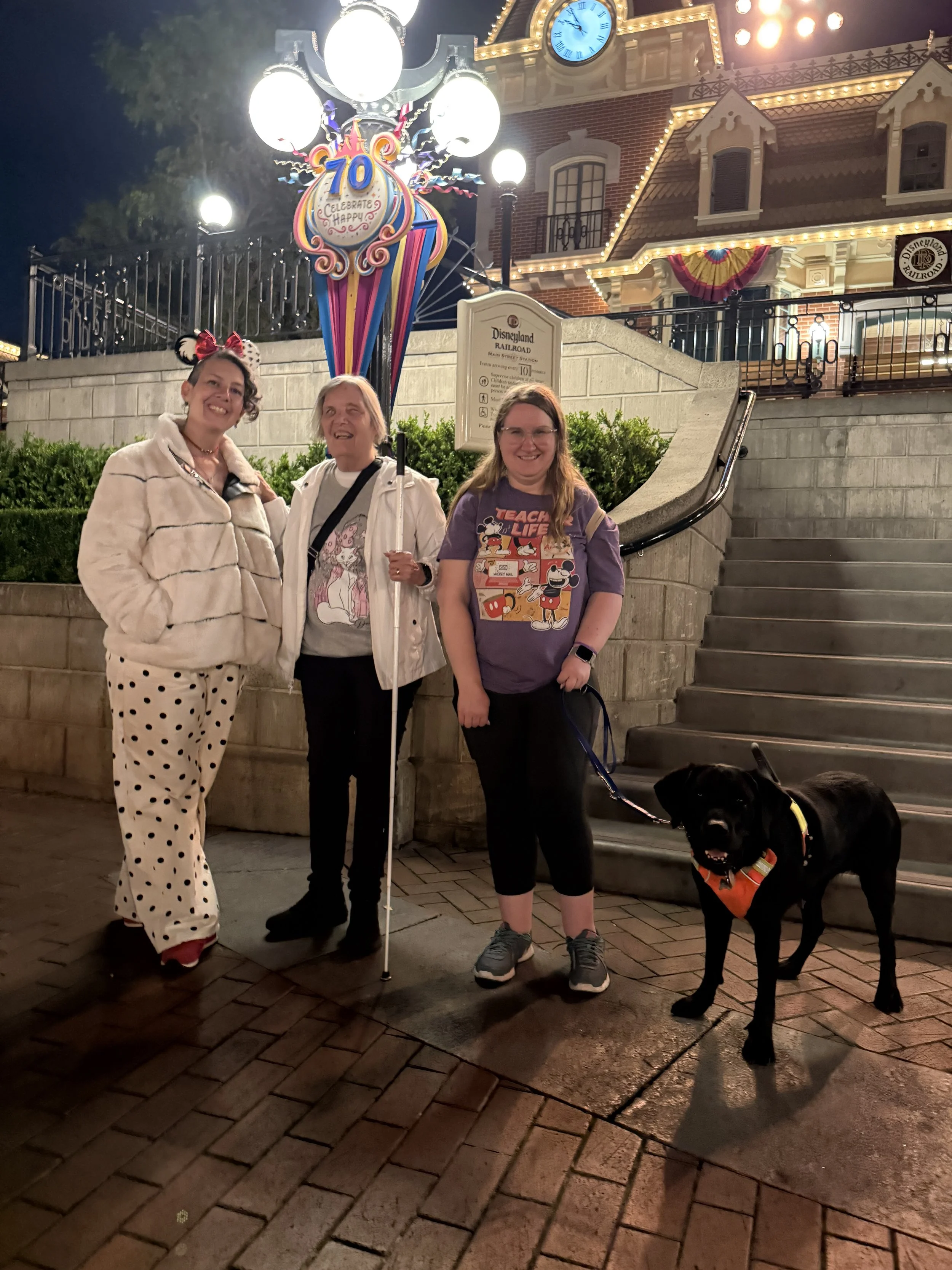 Kellie, Debi, Lindsay, and Eve posing for a picture while the Disneyland railway is behind them.