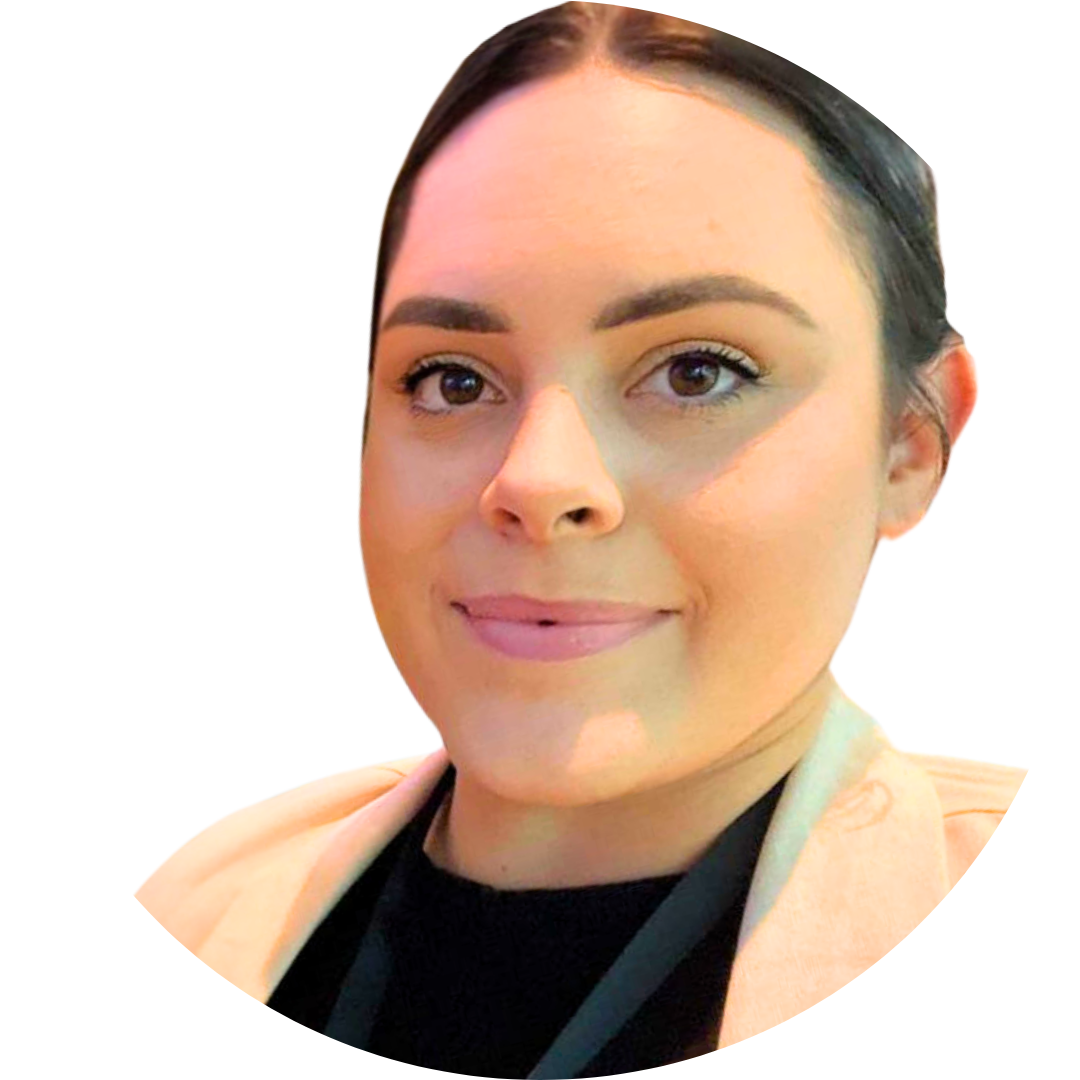 Close-up of a woman's face with dark hair pulled back, wearing a beige jacket and black top, smiling slightly, with a white background.