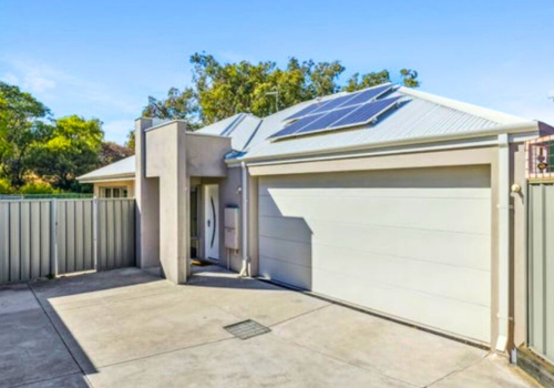 Modern house with solar panels on the roof and a large garage door.