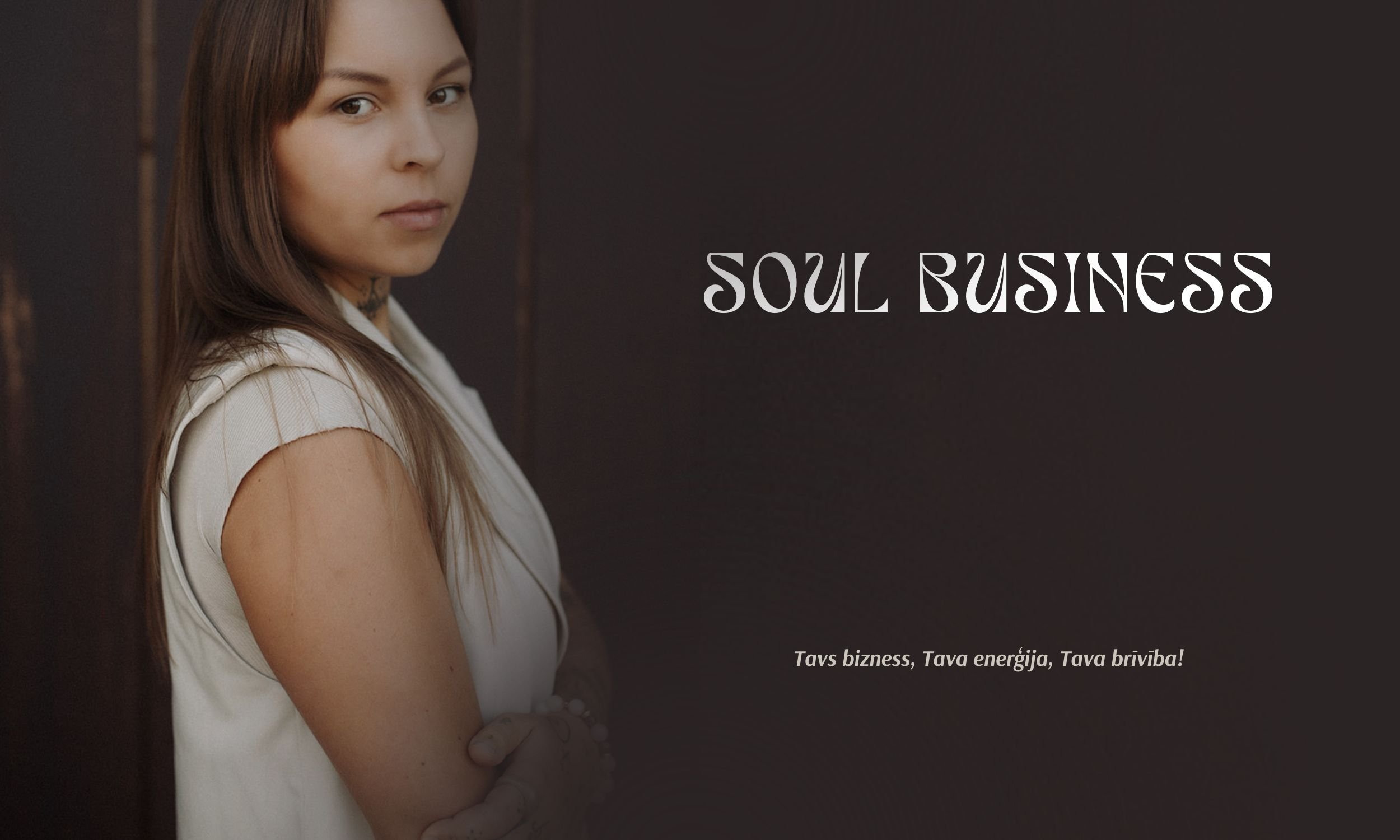 A woman with long brown hair looking at the camera, standing against a dark background. The text 'SOUL BUSINESS' appears on the right side, with a smaller phrase in a different language below.