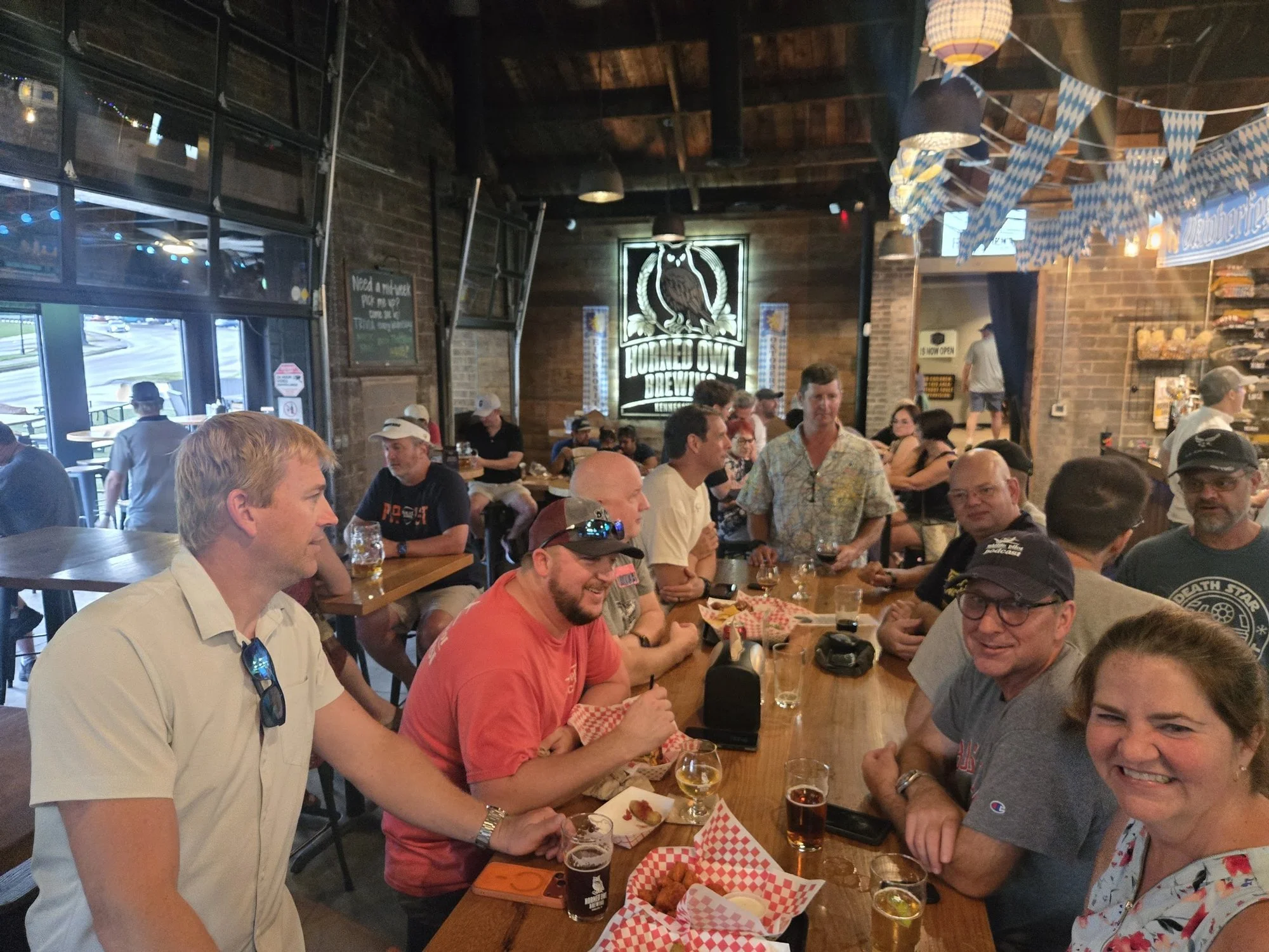 Listeners and hosts around a long table at a brewery after the live show