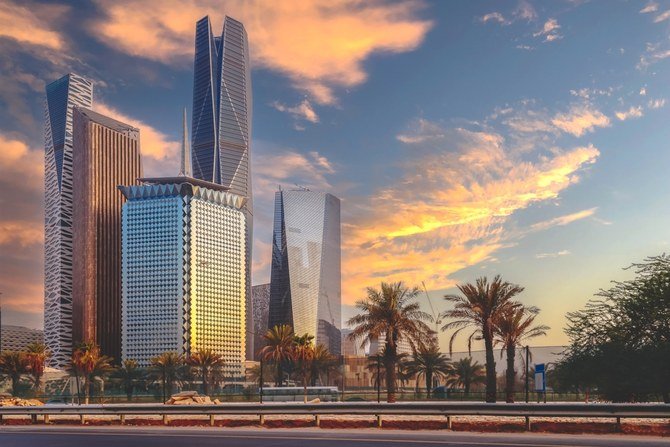 Skyscrapers and palm trees along a highway at sunset in an urban cityscape.