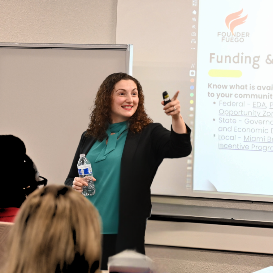 Woman with fist pump in front of brick wall with business writing