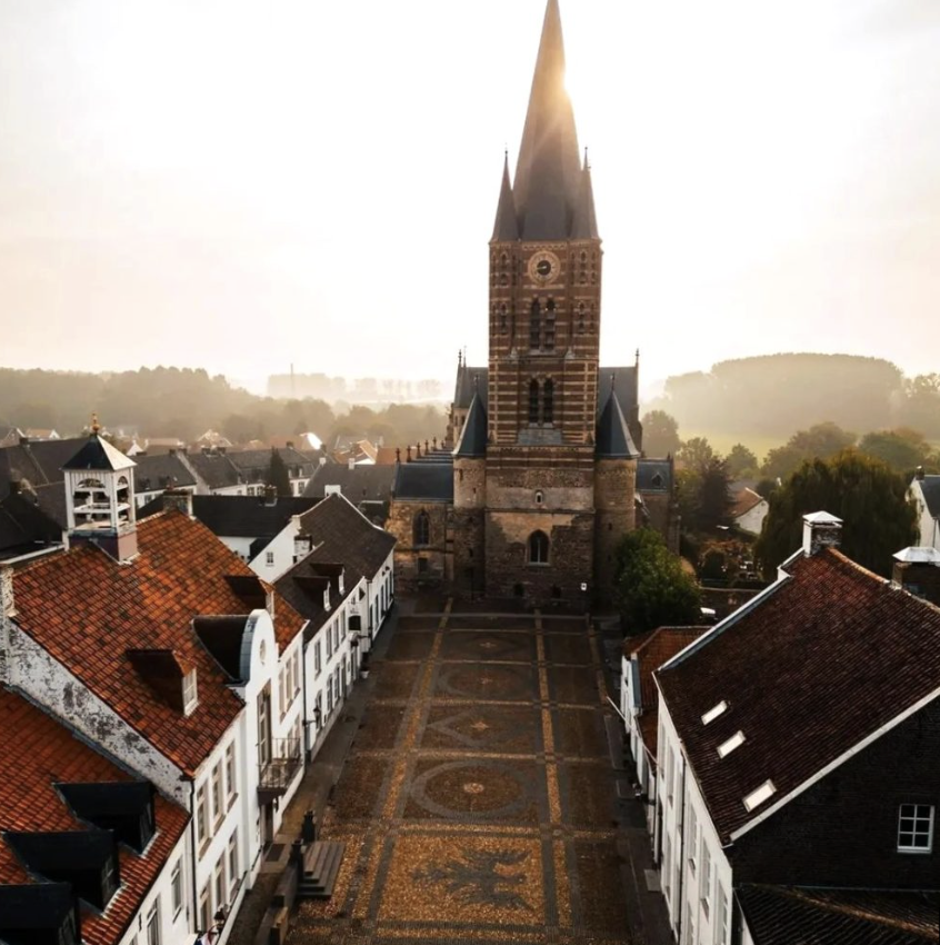 Aerial view of the historic Wijngaard in Thorn, lined with white houses and leading towards the Abbey Church in the warm evening light.