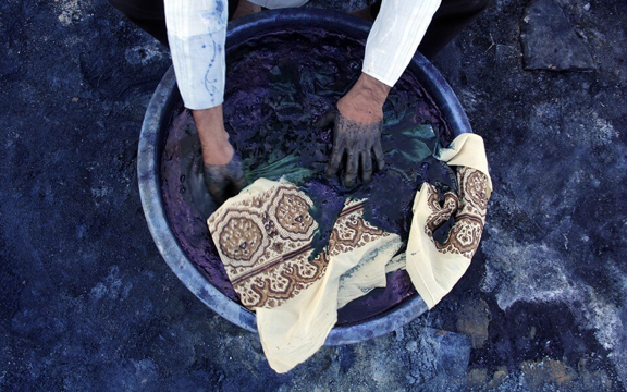 Hands dyeing textiles in a traditional indigo bath, reflecting repetition, material knowledge, and centuries-old craft practice.