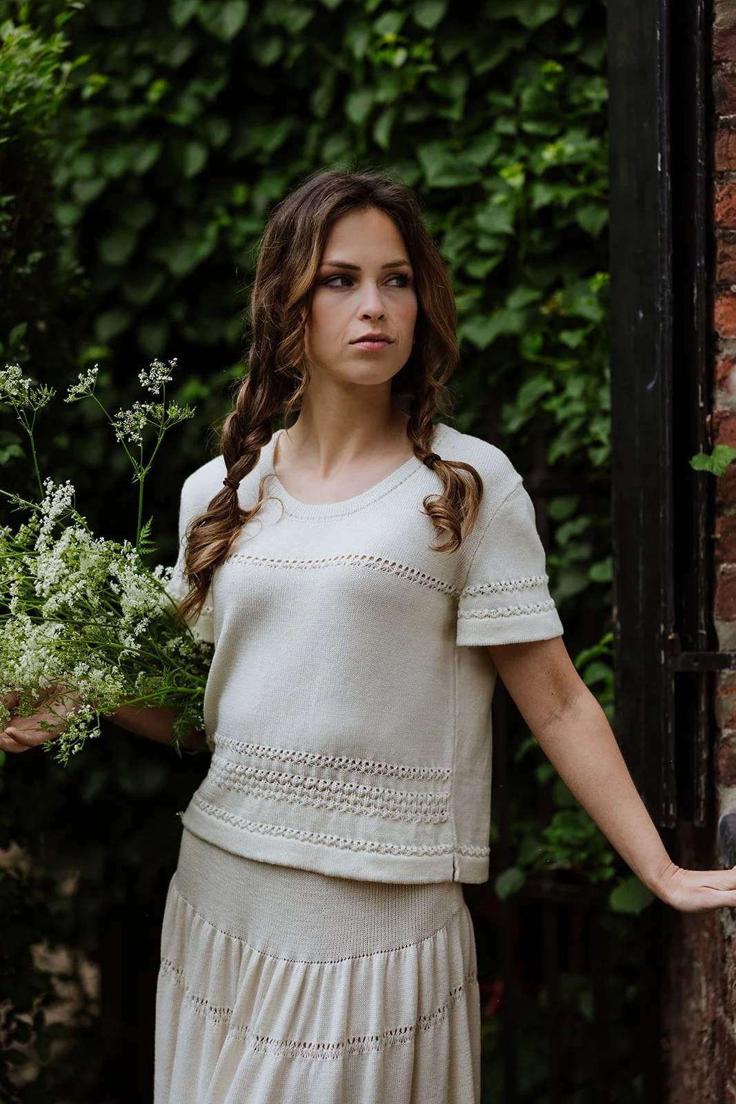 Woman wearing an ivory knitted top with delicate lace details from the Studio Myr Sweeties collection.