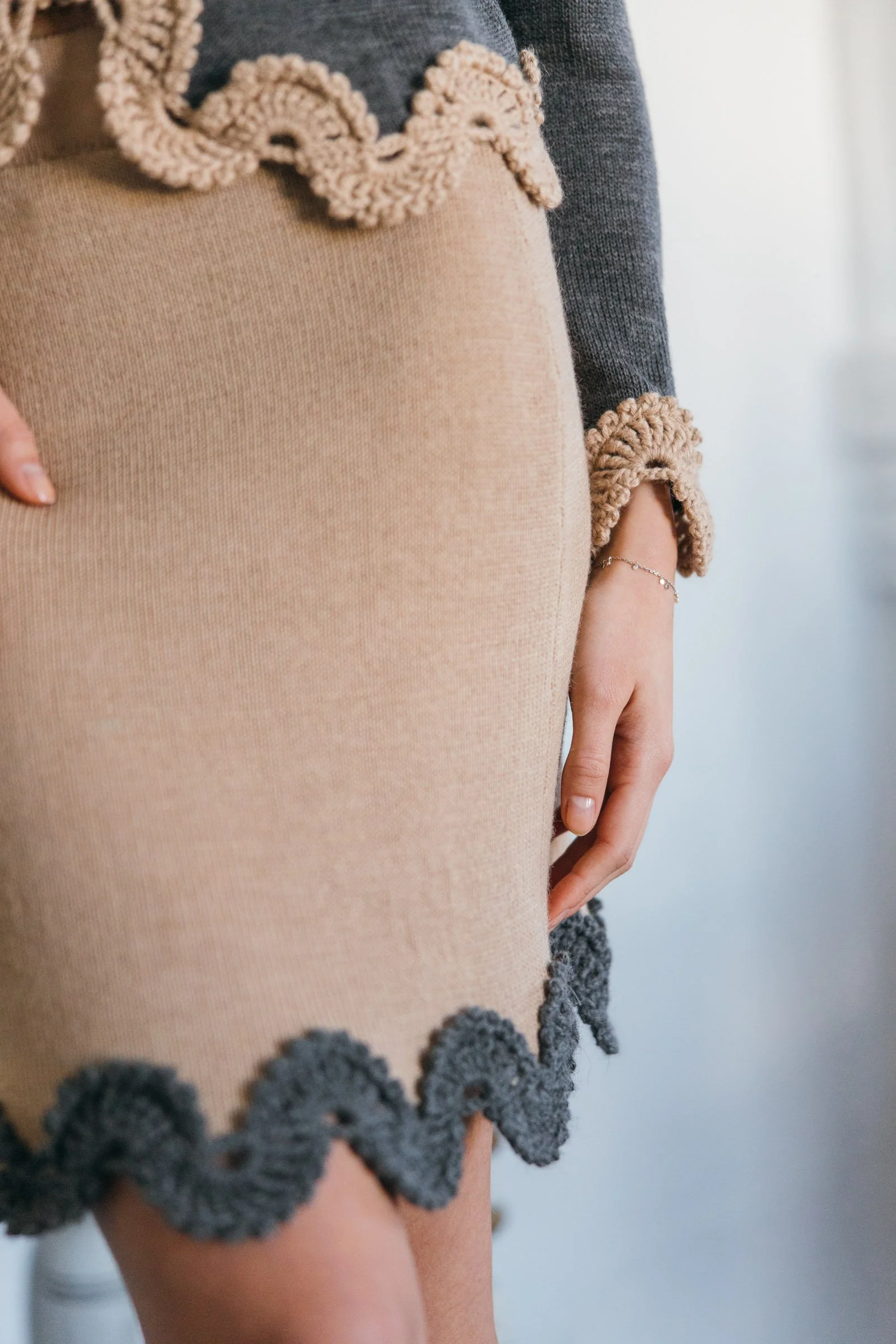 Studio Myr BAROQUE – Close-up of the Gabriella skirt showing the smooth beige Merino knit, gently fitted silhouette and grey crochet lace hem