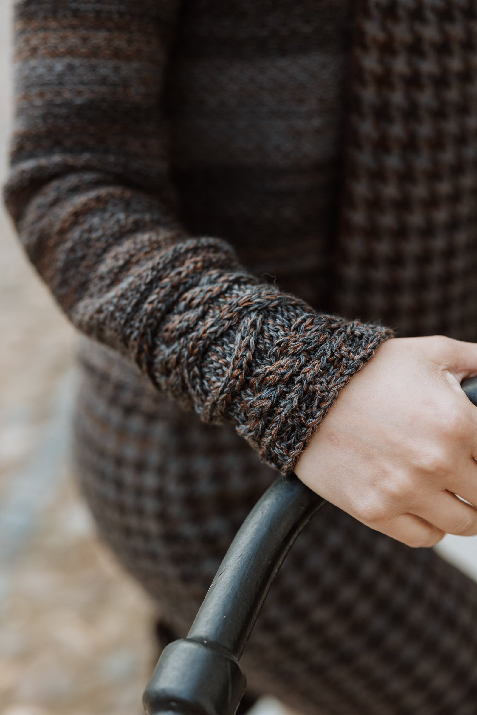 Detail of a knitted sleeve and hand, emphasising texture, softness, and wearability.