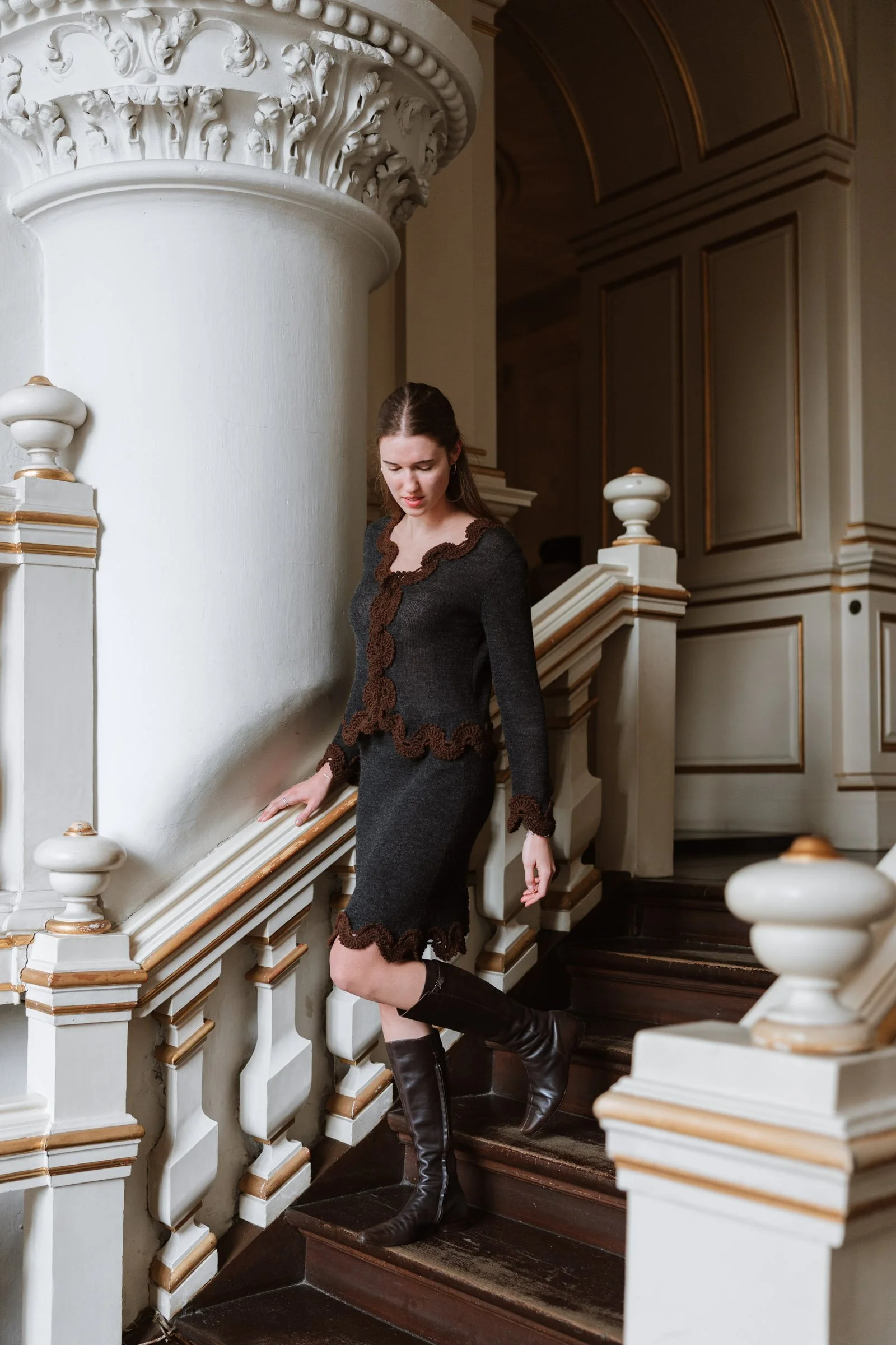 Studio Myr BAROQUE – Model wearing the Francisca skirt in charcoal grey with chocolate brown crochet lace, styled with a matching jacket on a historic staircase