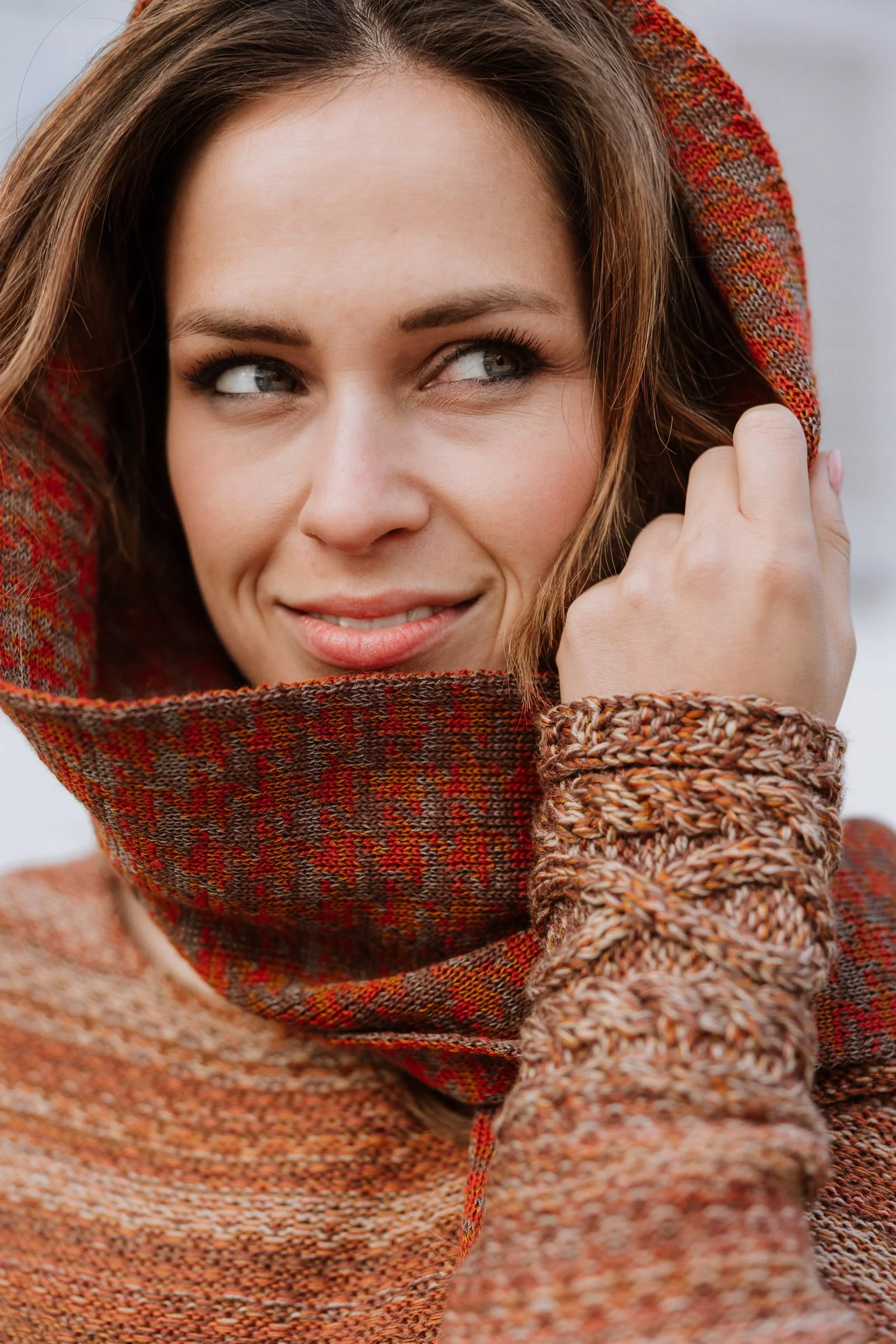 Detail of a knitted scarf wrapped around the face, emphasising colour depth and tactile quality.