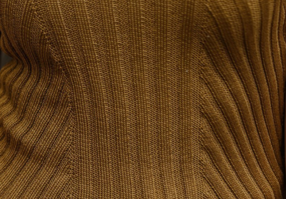 Detailed view of organic cotton rib knit in rich earthy brown tones, highlighting the structured texture and natural character of the material.