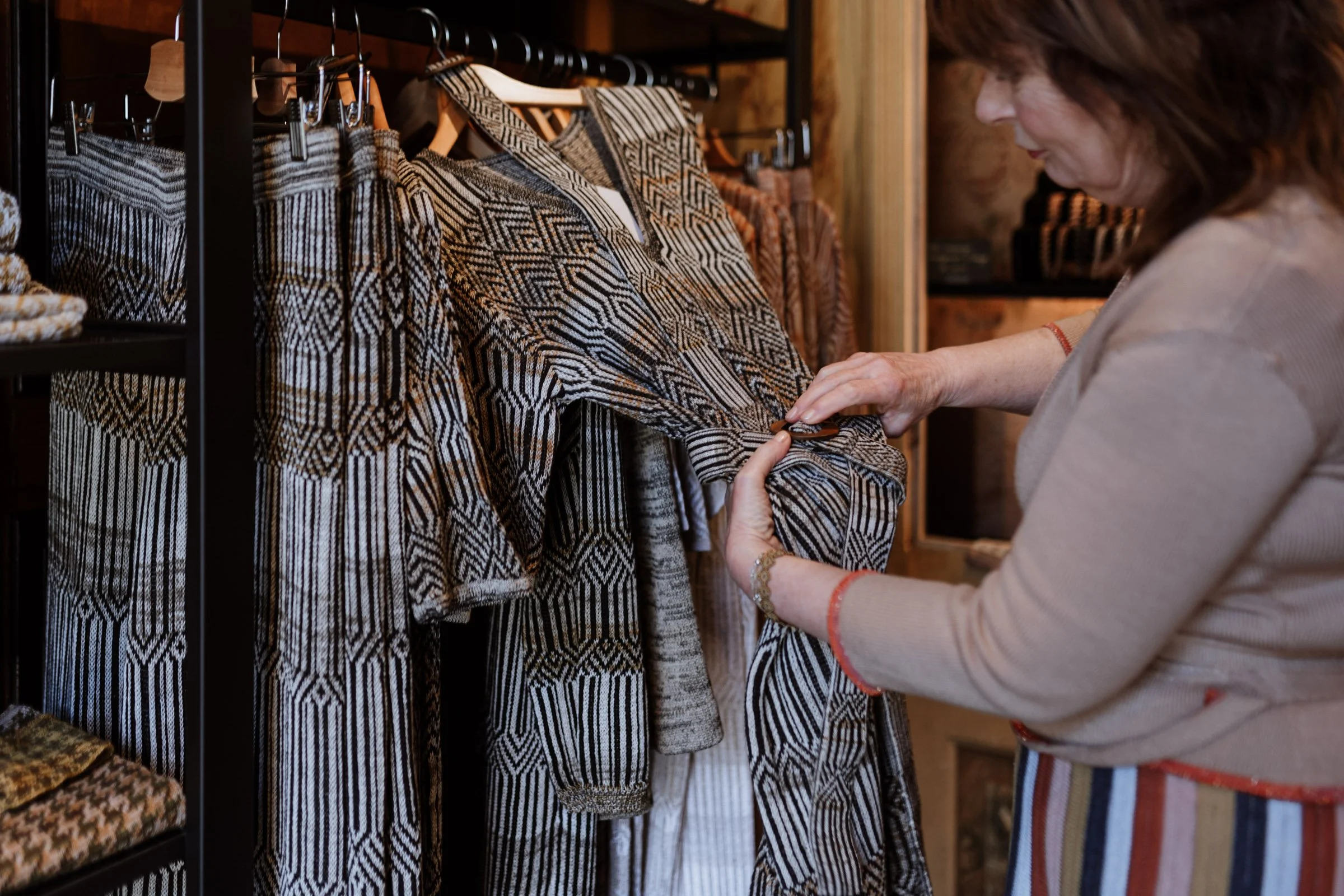 Studio Myr designer inspecting hand-finished knitwear in the boutique — jacquard garments made from natural, responsibly sourced fibres.