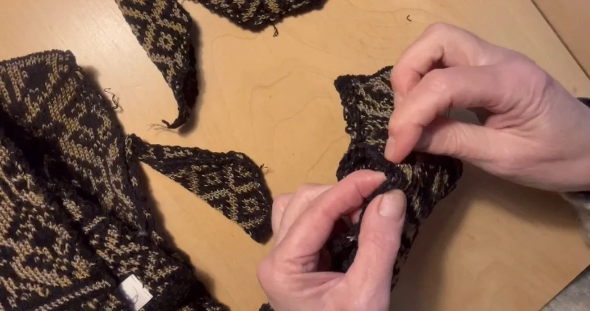 Hand-finishing a Studio Myr jacquard knitwear piece — designer meticulously closing seams and shaping details by hand.