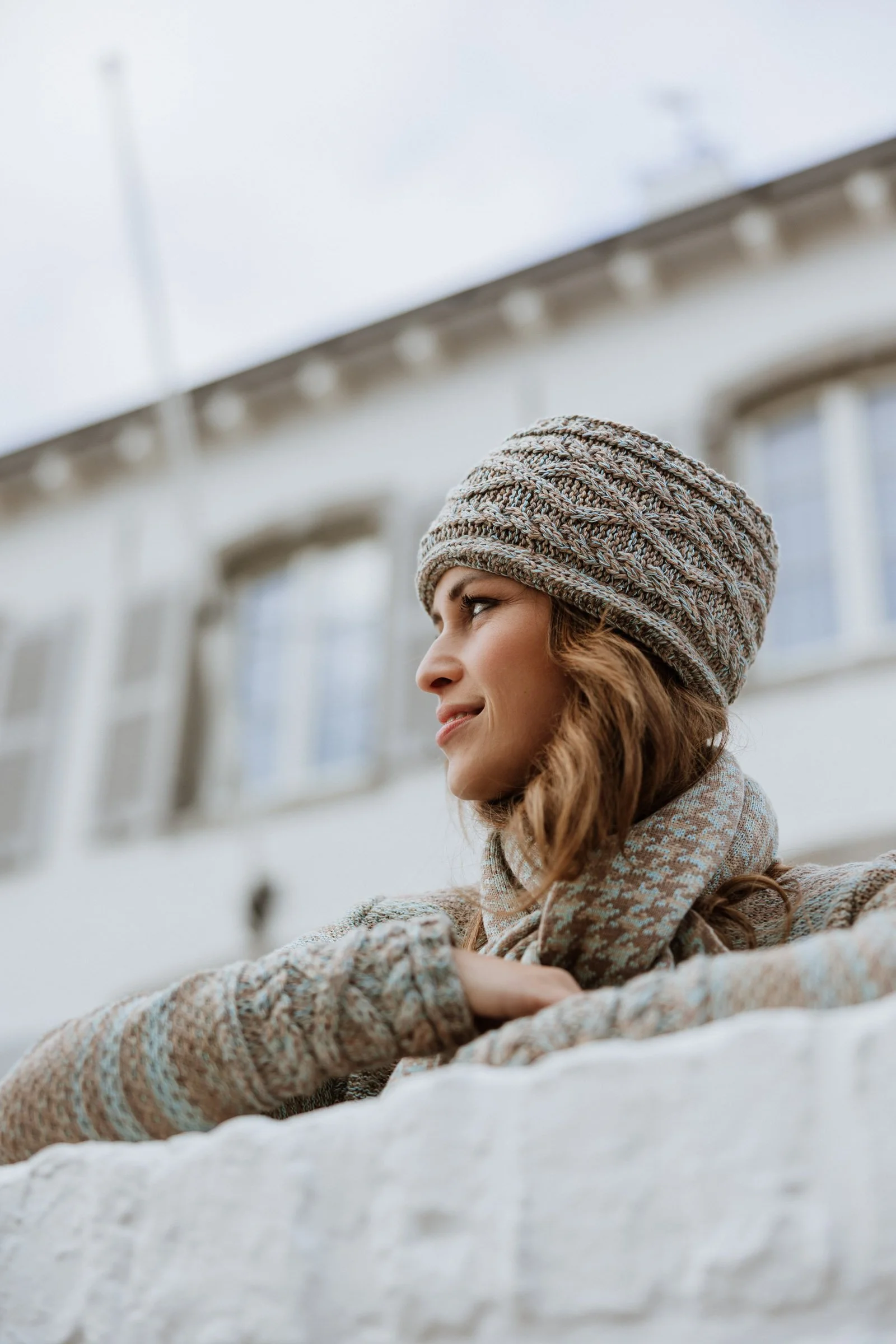 Model wearing a Studio Myr knit headband  and sweater Aran in soft natural shades, photographed outdoors in quiet daylight.