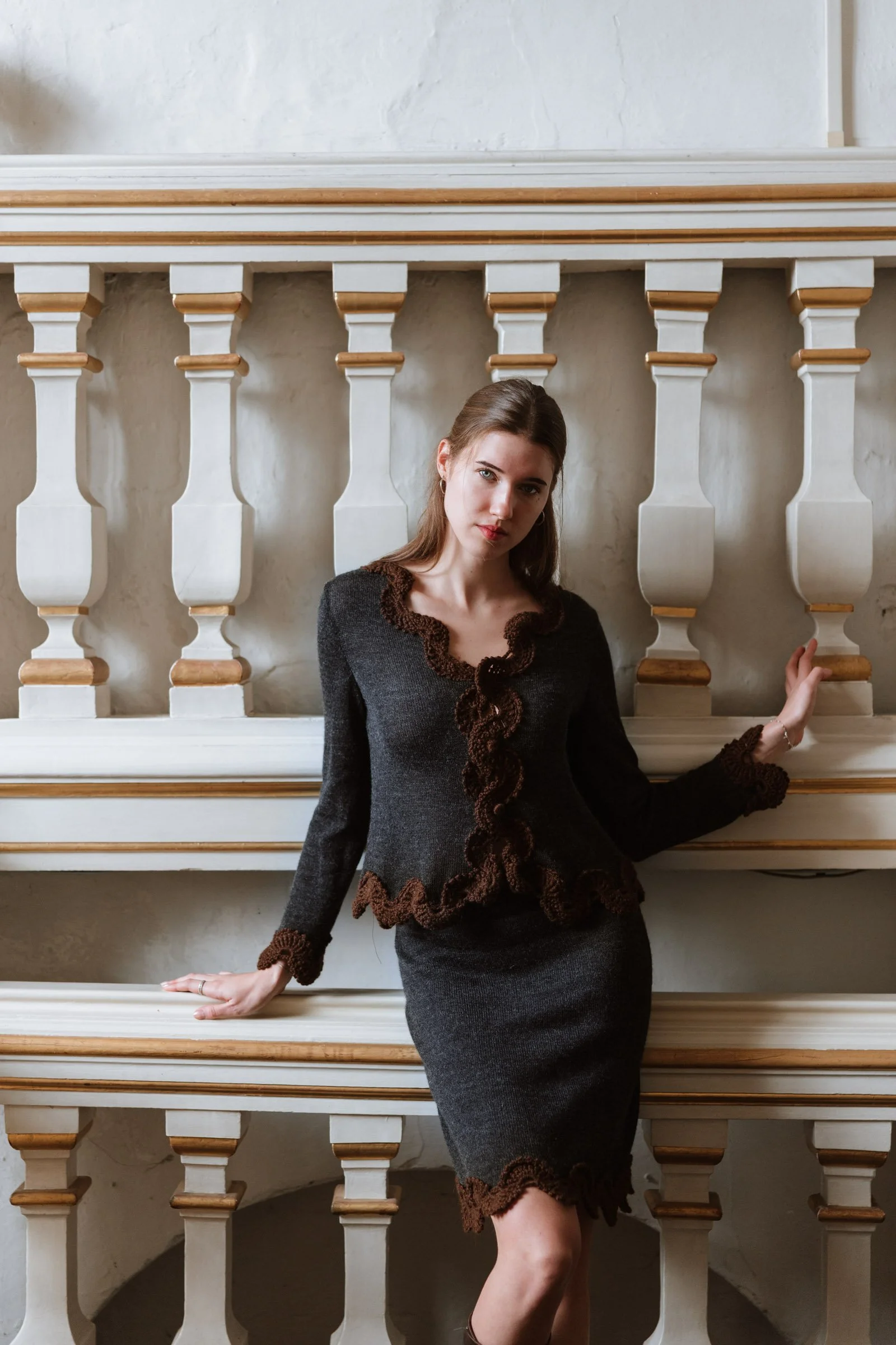 Studio Myr BAROQUE – Model wearing the Francisca jacket in charcoal grey with chocolate brown crochet lace, styled with a matching skirt