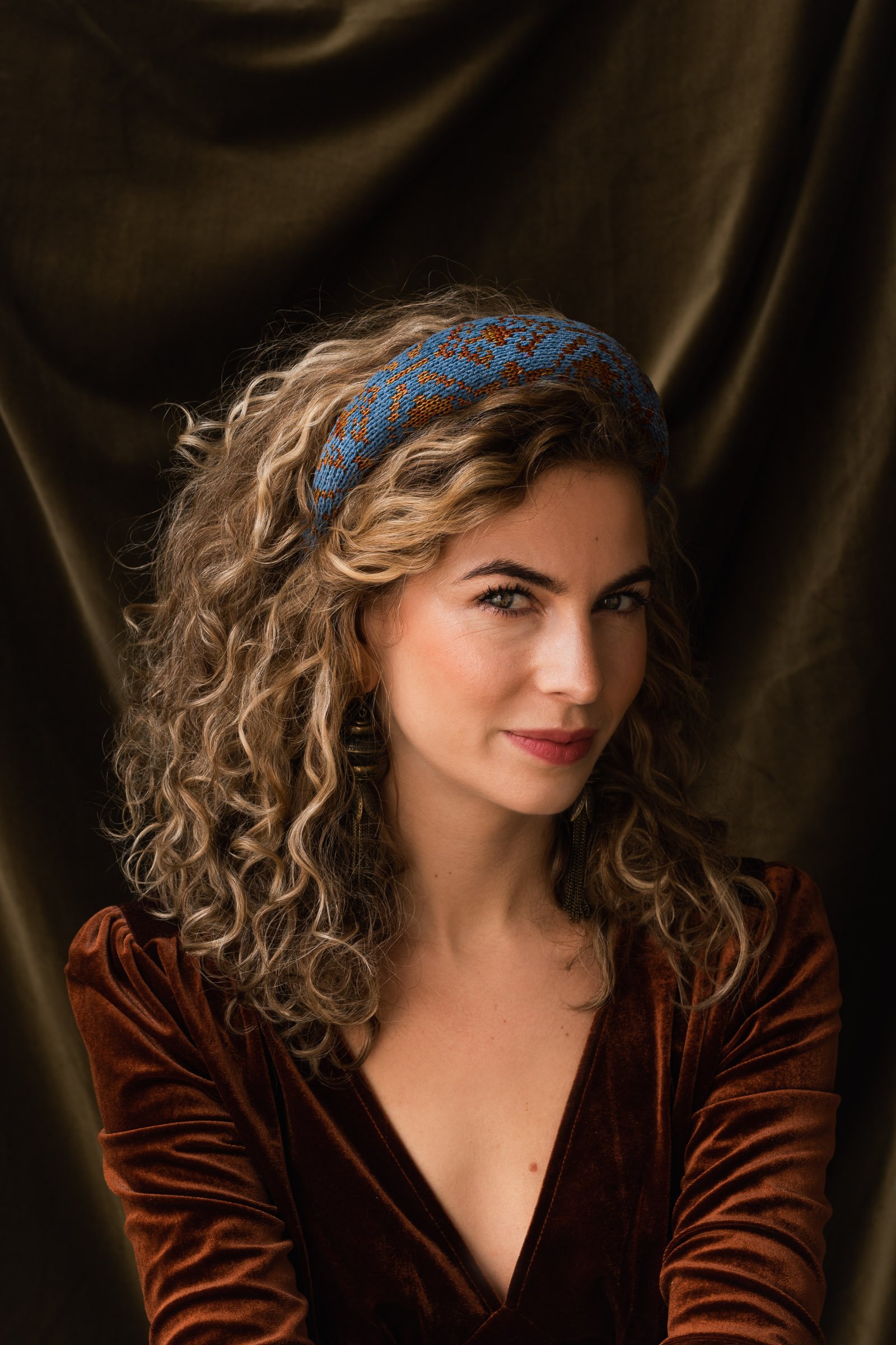 Model wearing the Studio Myr Veronica velvet diadem in blue and copper tones — luxury knitwear headband handmade in the Netherlands