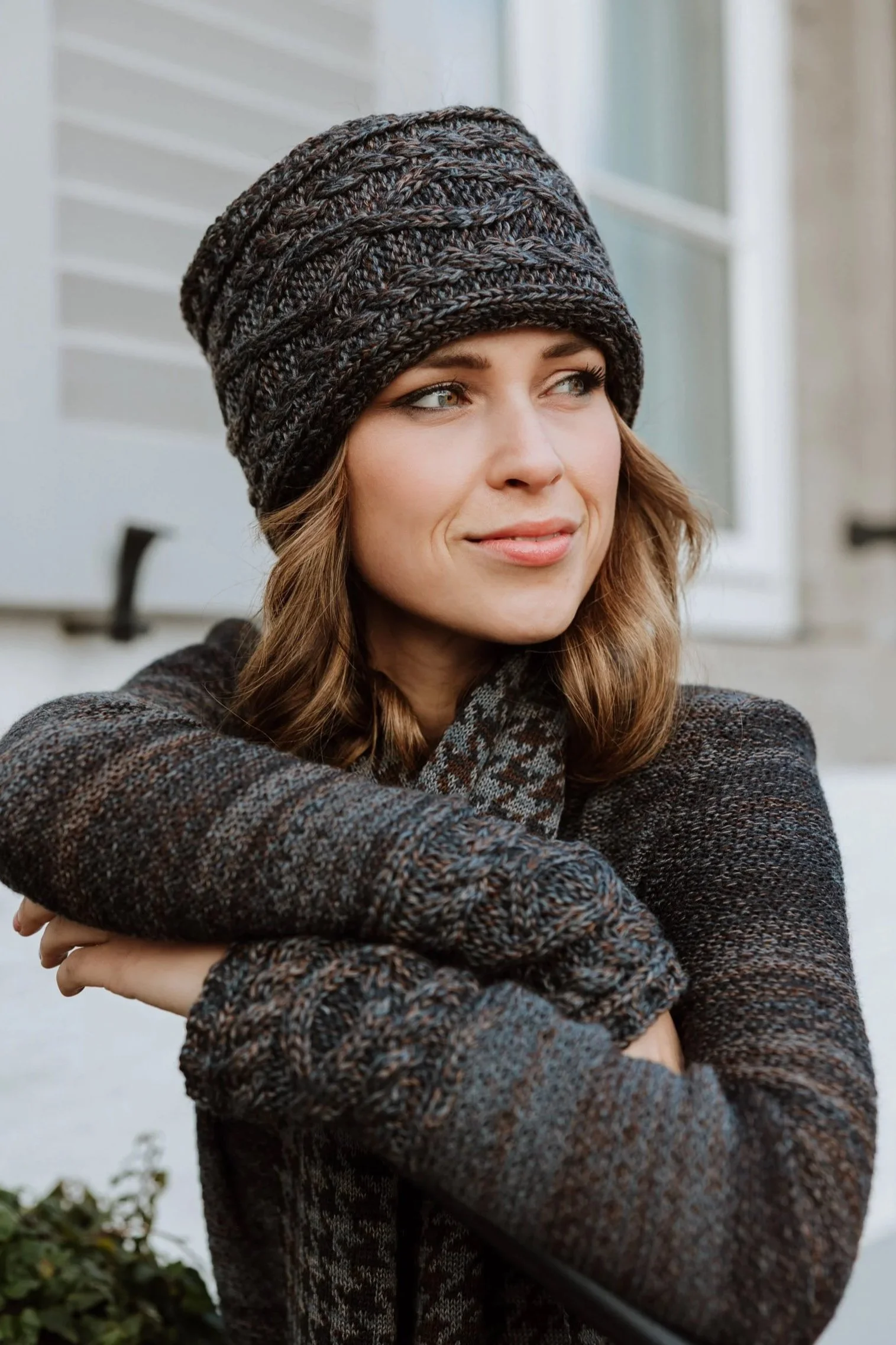 Woman wearing Studio Myr Aran knit sweater and matching headband, showcasing classic cable patterns in refined natural yarns