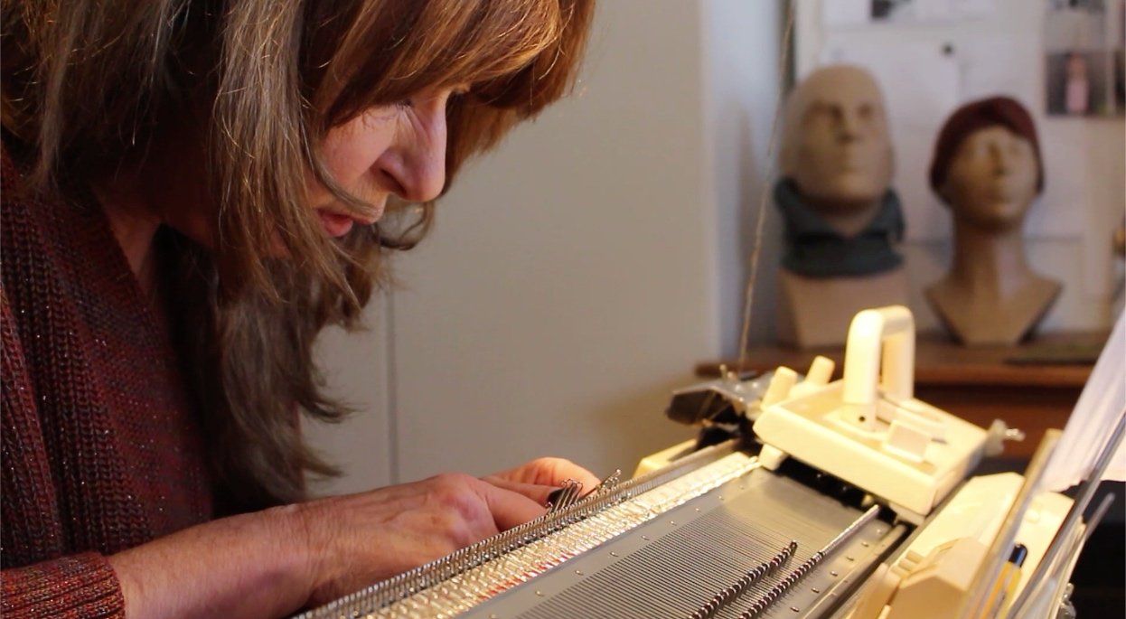 Designer Miriam Lenarts working at a knitting machine in her studio, reflecting the hands-on craftsmanship and origins of ethical luxury knitwear at Studio Myr