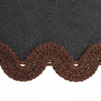 Detail of the Francisca jumper hem featuring intricate chocolate brown hand-crocheted Baby Alpaca lace with a scalloped pattern on charcoal grey Merino wool.