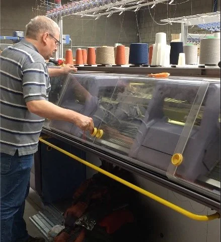 Craftsperson operating a knitting machine at KNIT‑IT in Lichtenvoorde, reflecting local production, technical skill, and responsible scale
