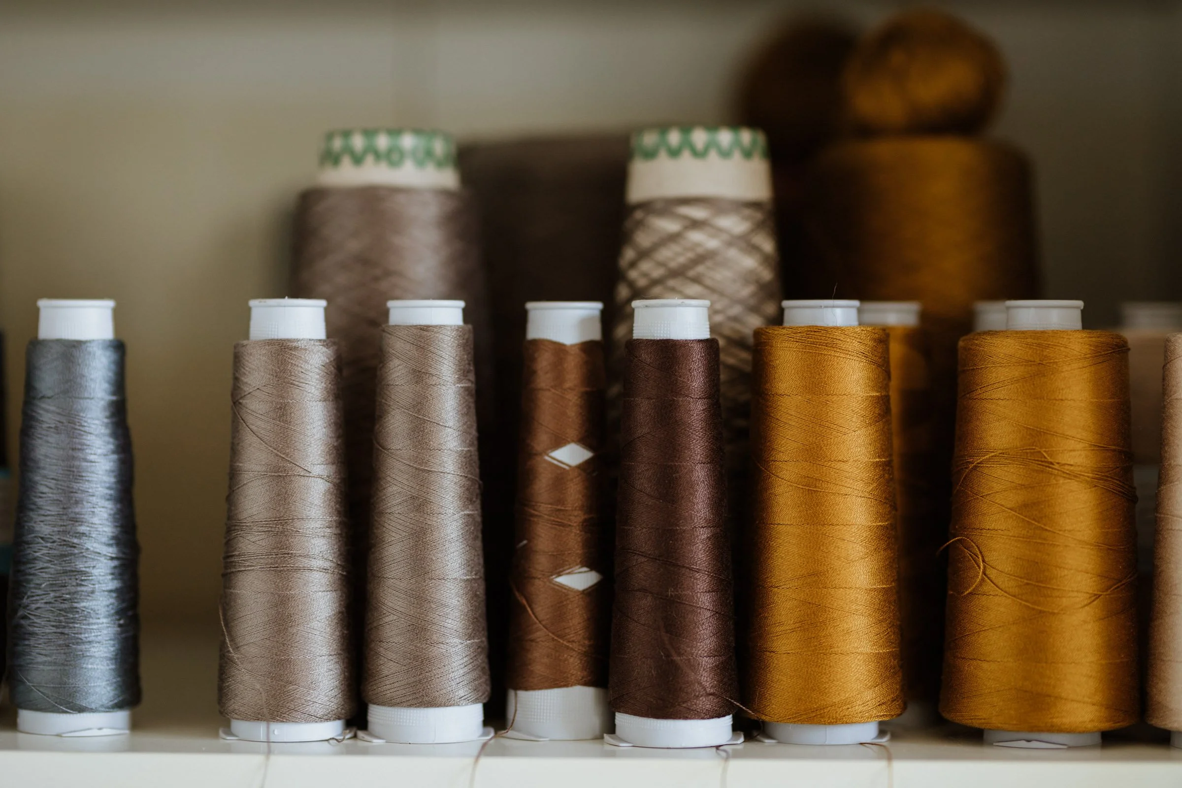 Cones of natural, responsibly sourced yarns in warm neutral tones — Merino, linen, and cotton fibres used in Studio Myr’s small-batch knitwear.