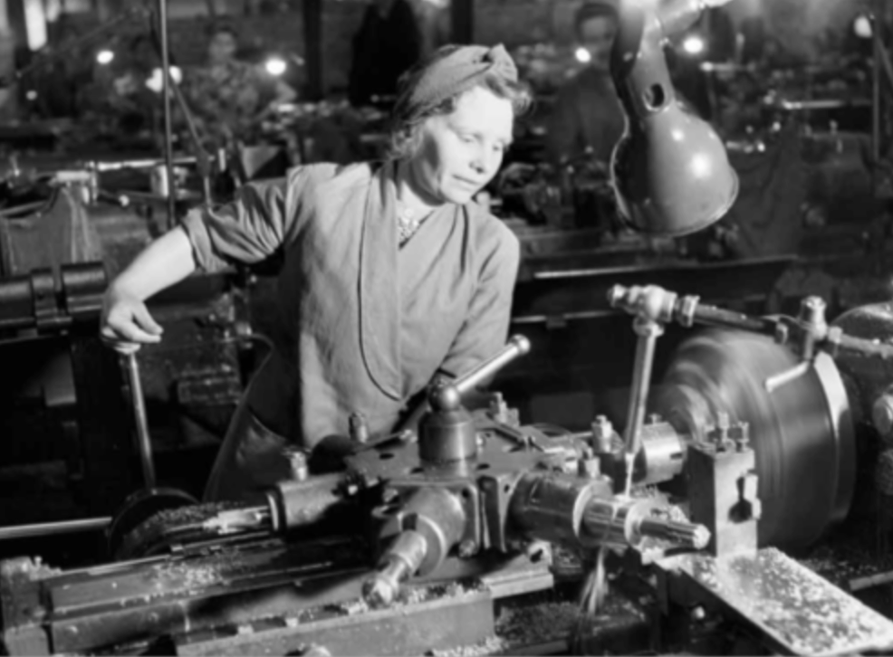Female factory worker wearing a protective headscarf while operating machinery in a British ammunition plant during World War II, 1942 — early utilitarian use of headbands for safety and function.