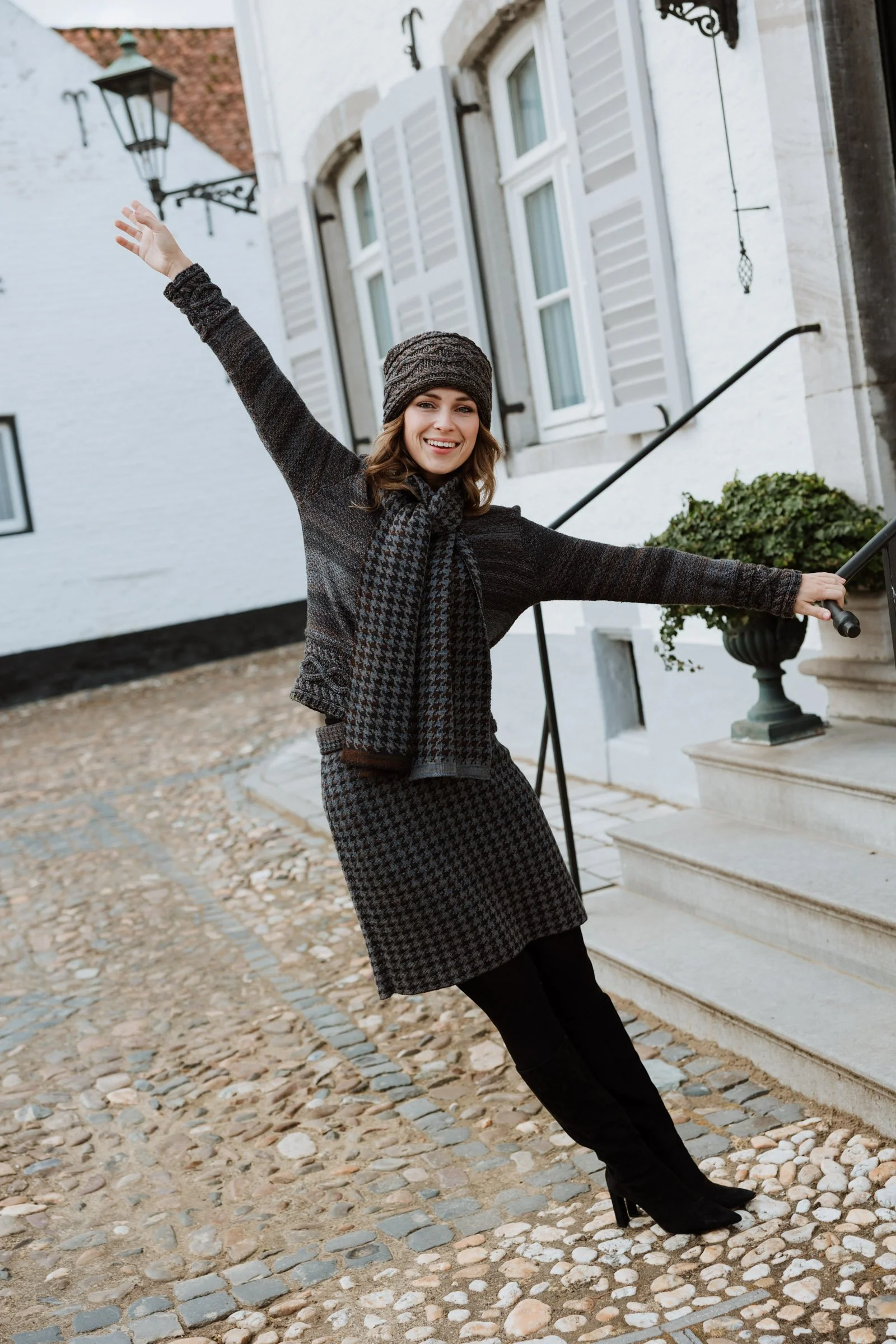 Model wearing a Studio Myr knit dress and headwear, photographed in the streets of Thorn, expressing movement and ease.
