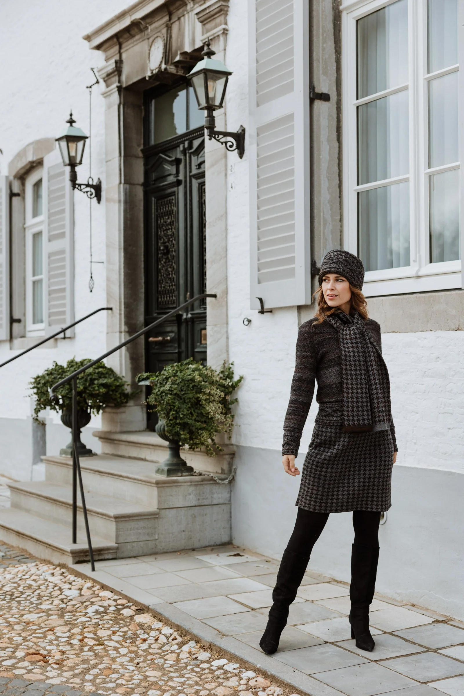Model wearing a Studio Myr pied-de-poule knit skirt and scarf, photographed in the historic streets of Thorn.
