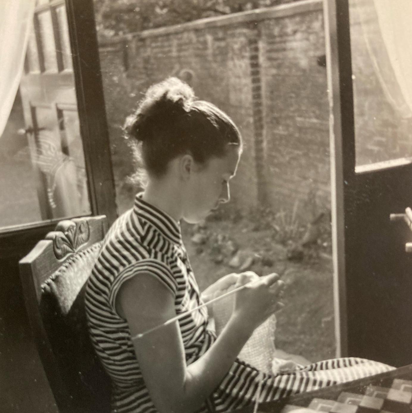Archival photograph of a woman knitting by a window, symbolising the domestic craft traditions that inspired Studio Myr.