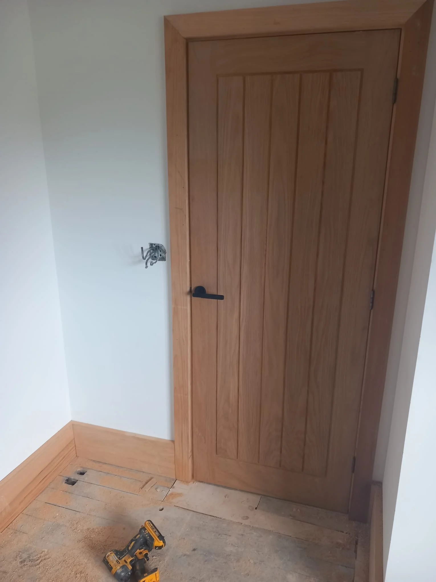 A partially installed wooden door with tools and construction materials on a dusty floor, suggesting ongoing home renovation or carpentry work. joinery based in rotherham, sheffield, doncaster, barnsley. worktop