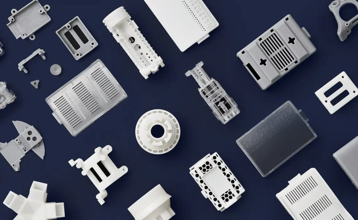 Diverse vita och grå 3D-printade polymerdelar arrangerade på en blå bakgrund.