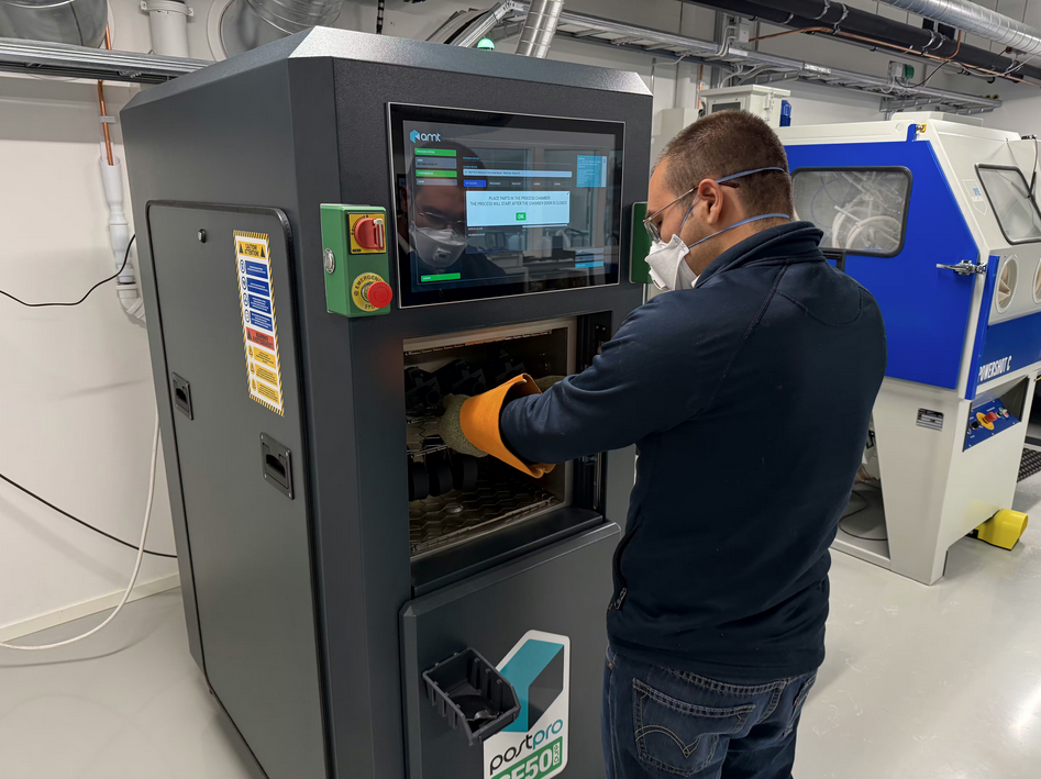 Operator using AMT vapor smoothing equipment for post processing 3D printed nylon parts at Norra AM