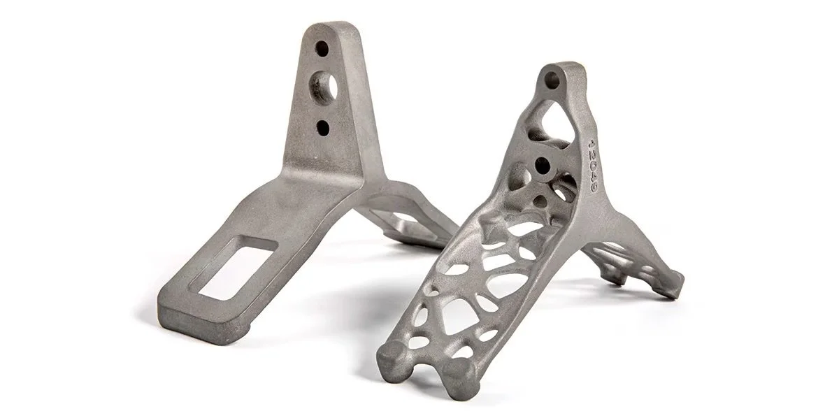 Två topologioptimerade 3D-printade metalldelar utformade för låg vikt och strukturell effektivitet.