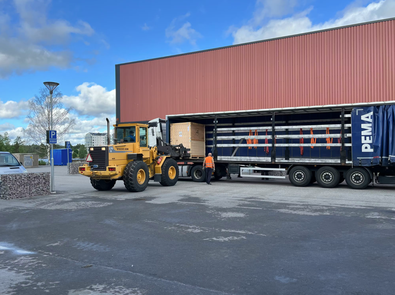 Delivery truck and loader outside Norra AM’s production facility during the arrival of the company’s first industrial machine.