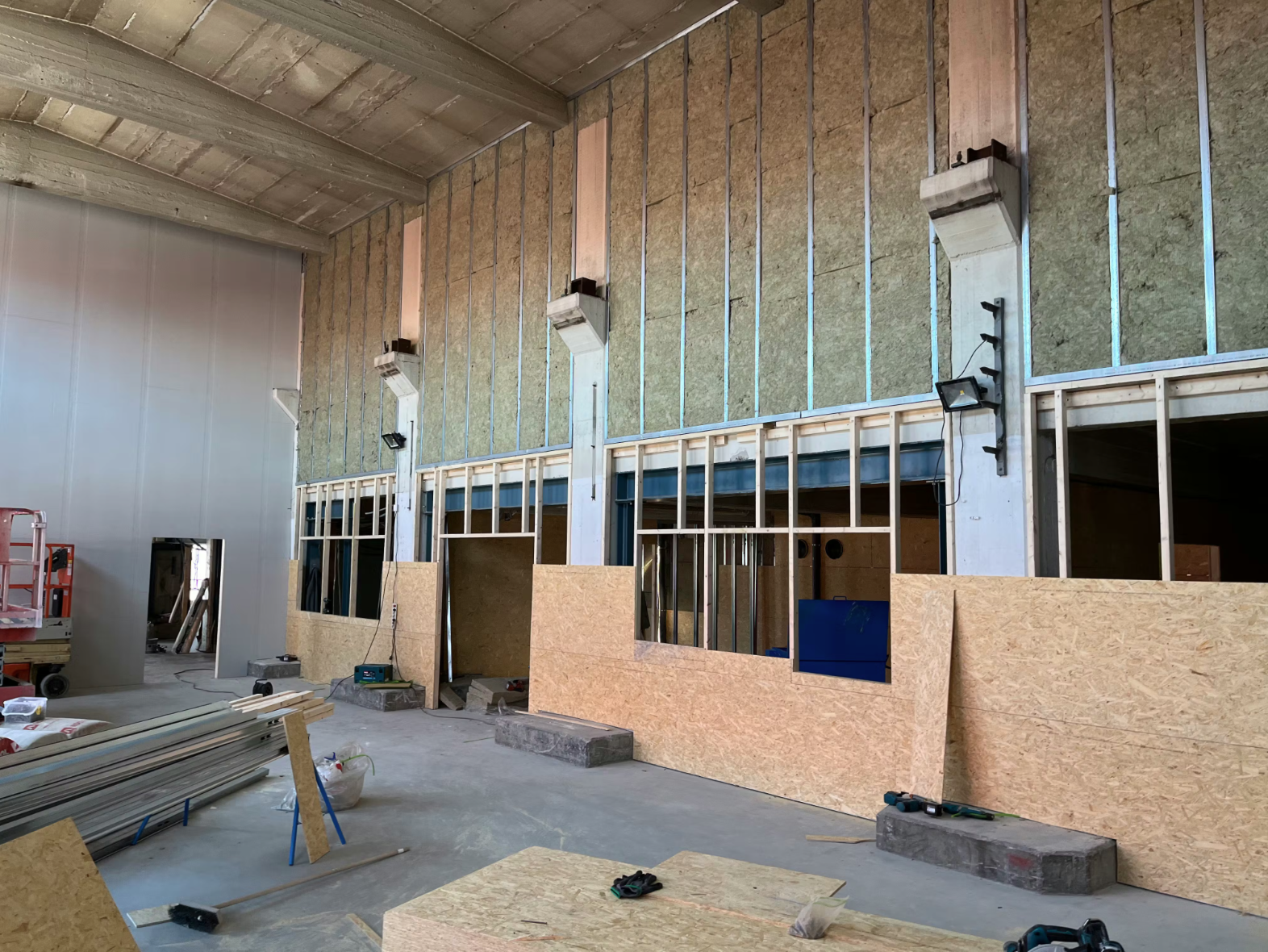Industrial production space under construction with wall framing, insulation, and preparation for additive manufacturing setup.
