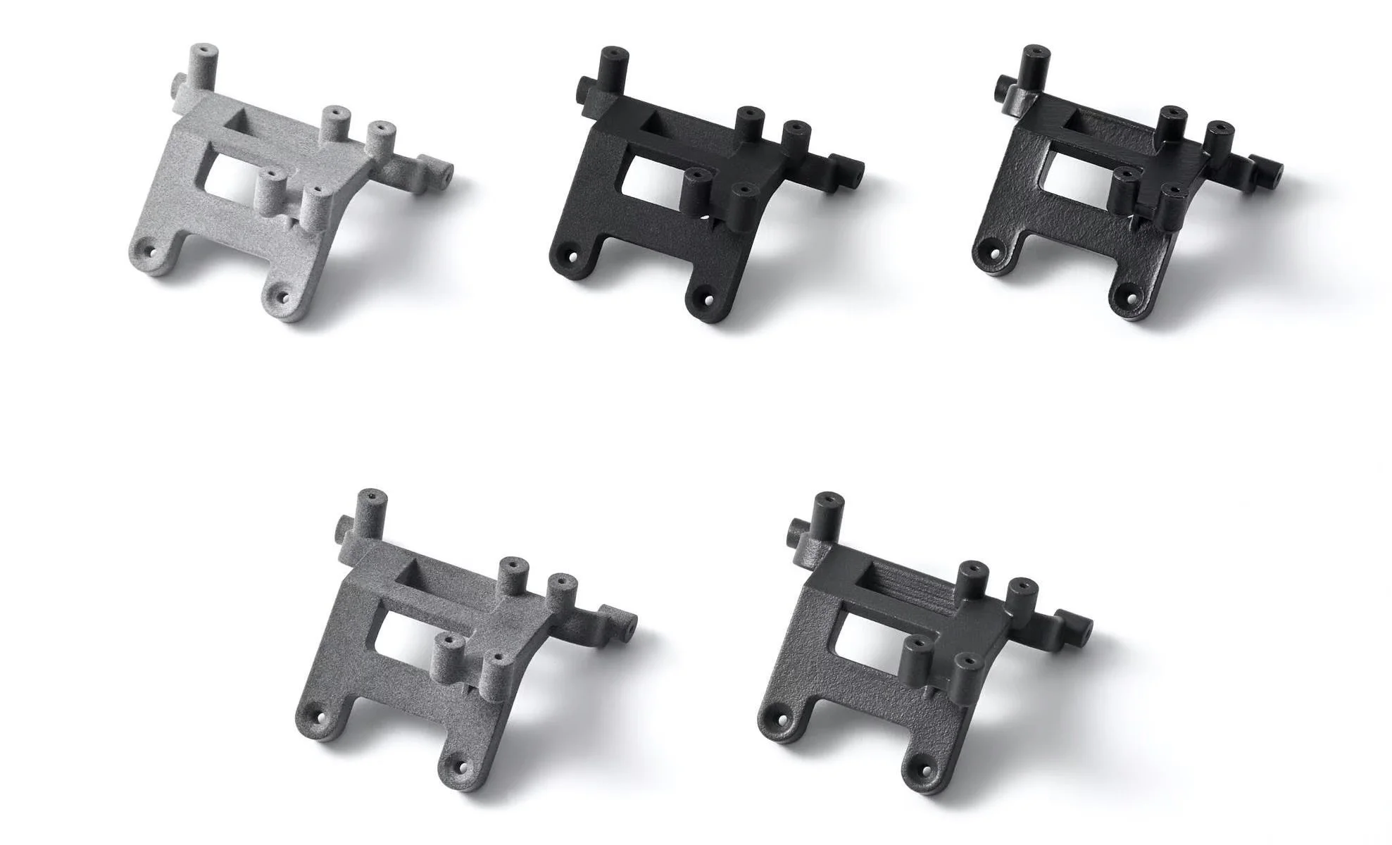 Fem svarta och grå 3D-utskrivna mekaniska fästen på en vit bakgrund, vart och ett med flera cylindriska förlängningar och monteringshål.